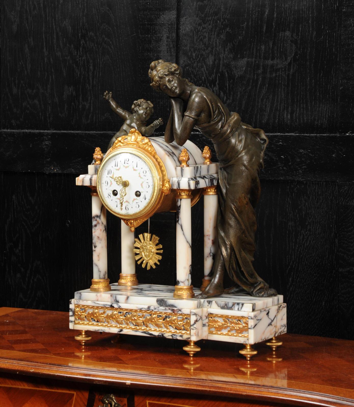 A stunning antique French portico clock featuring Amor and Venus, circa 1900. Amor presents Venus with roses but she turns away with a deaf ear. It is beautifully made in a white, blue and pink variegated specimen marble mounted with gilt metal. The