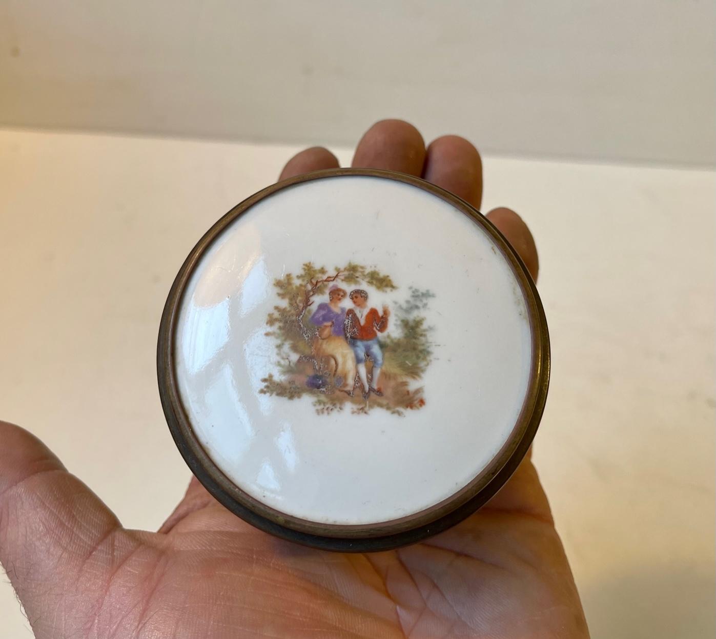 A beautiful vanity or powder trinket featuring a bronze lid with hand painted miniture romantic scene on white porcelain. The frosted glass bottom-part is decorated with hand painted flowers around its perimeter. Unknown French maker late 19th