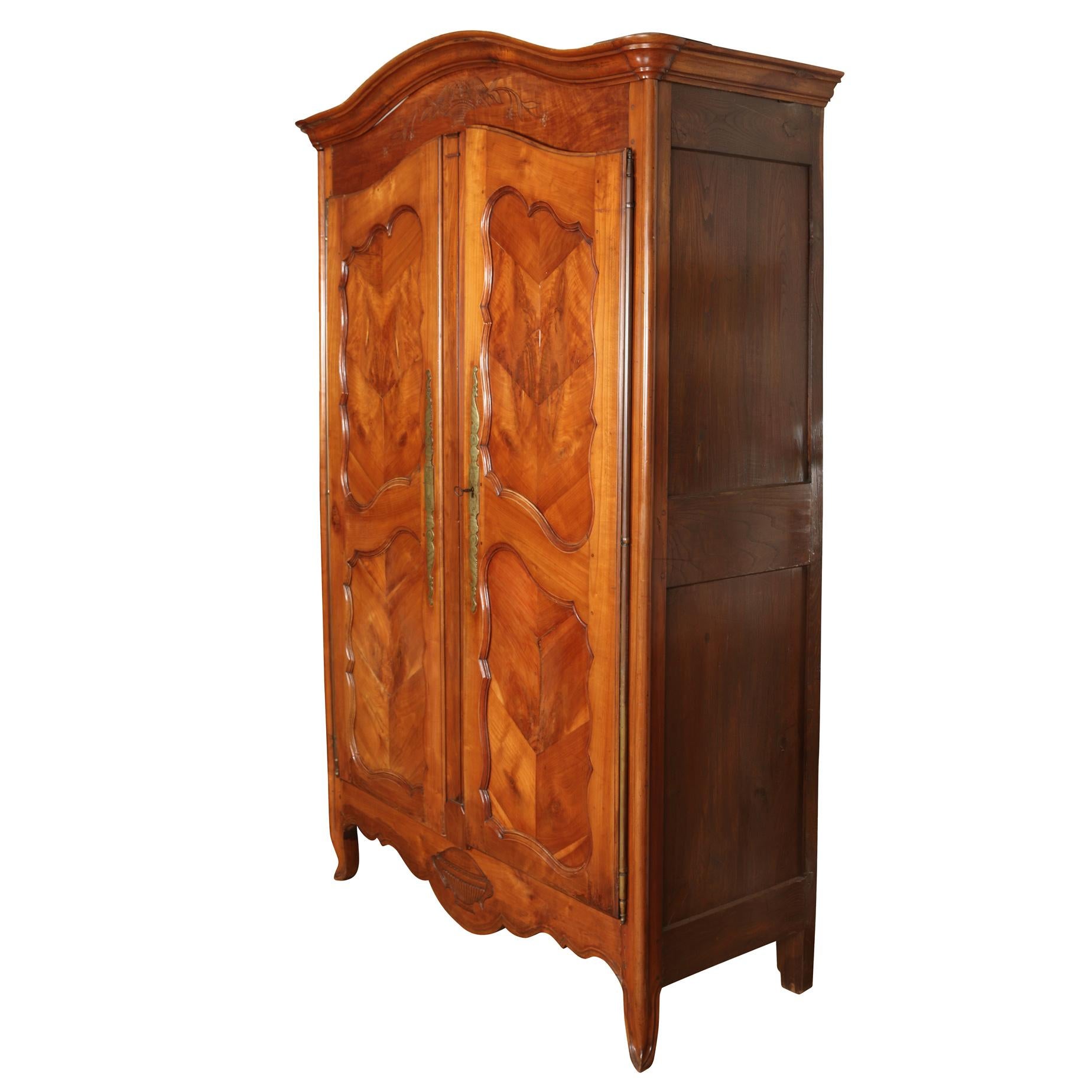 Antique French Provincial armoire with brass hardware. Opens to reveal two shelves for storage and open back for media. Top and apron is carved with floral, vine and bird details.