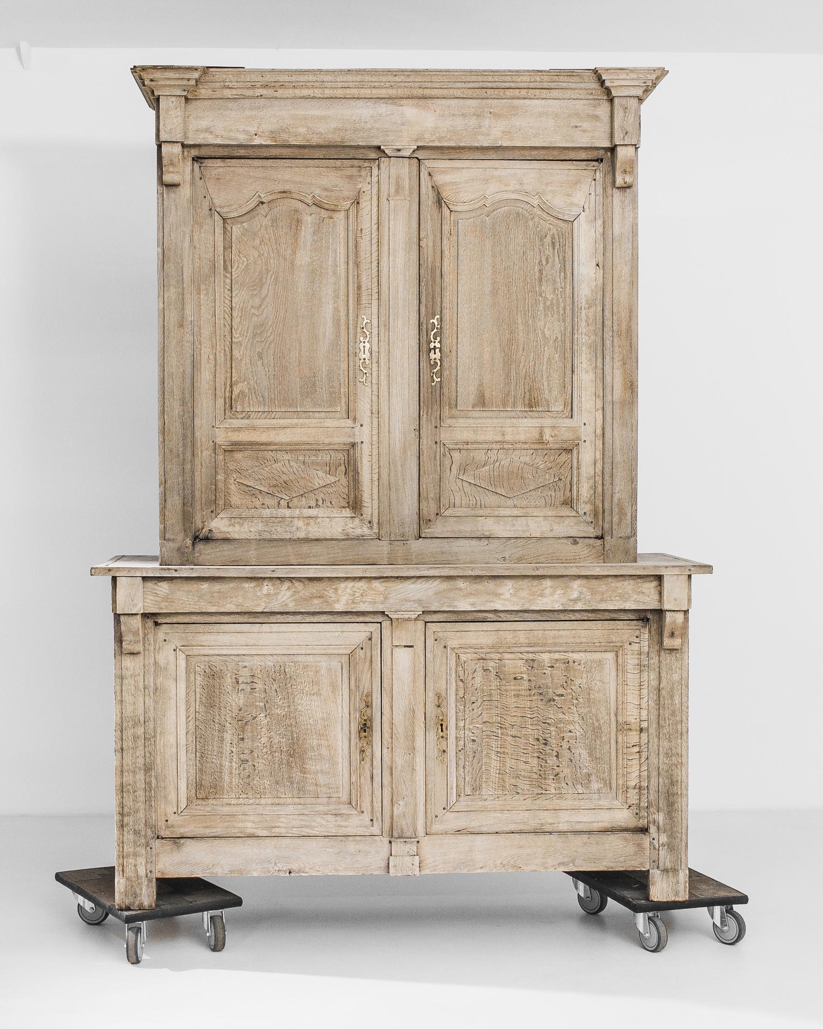 A bleached oak cabinet from France, produced circa 1860. A titan of a cabinet standing over seven feet six inches tall and featuring two tiers of double cabinets, this chest is sure to impress. A simple natural facade is broken up by brass