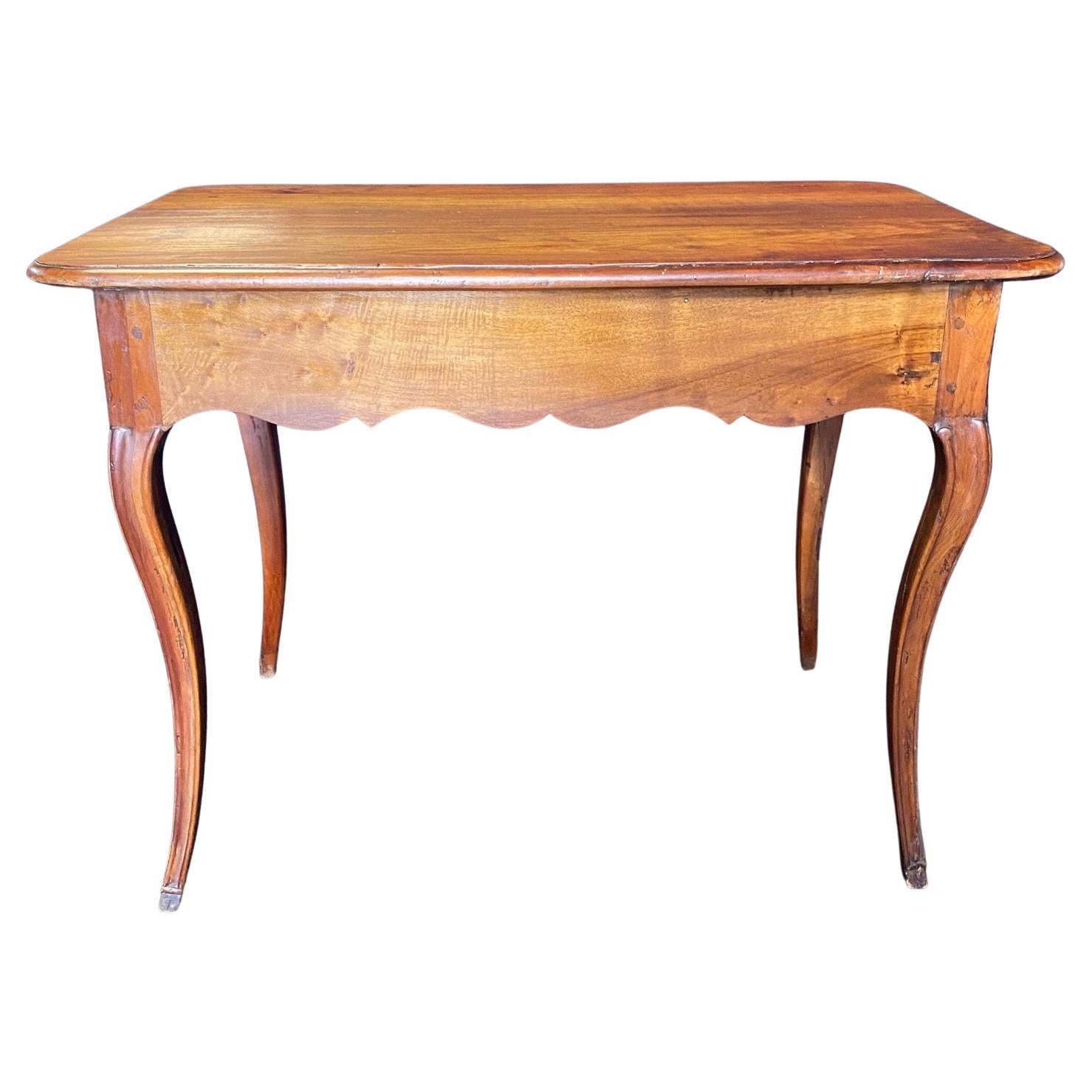 19th century cherry French side table or desk from the late 19th century; a beautiful example of the French Country design aesthetic. The table or desk has a beautifully carved scalloped apron on all four sides, making it ideal to sit in the center