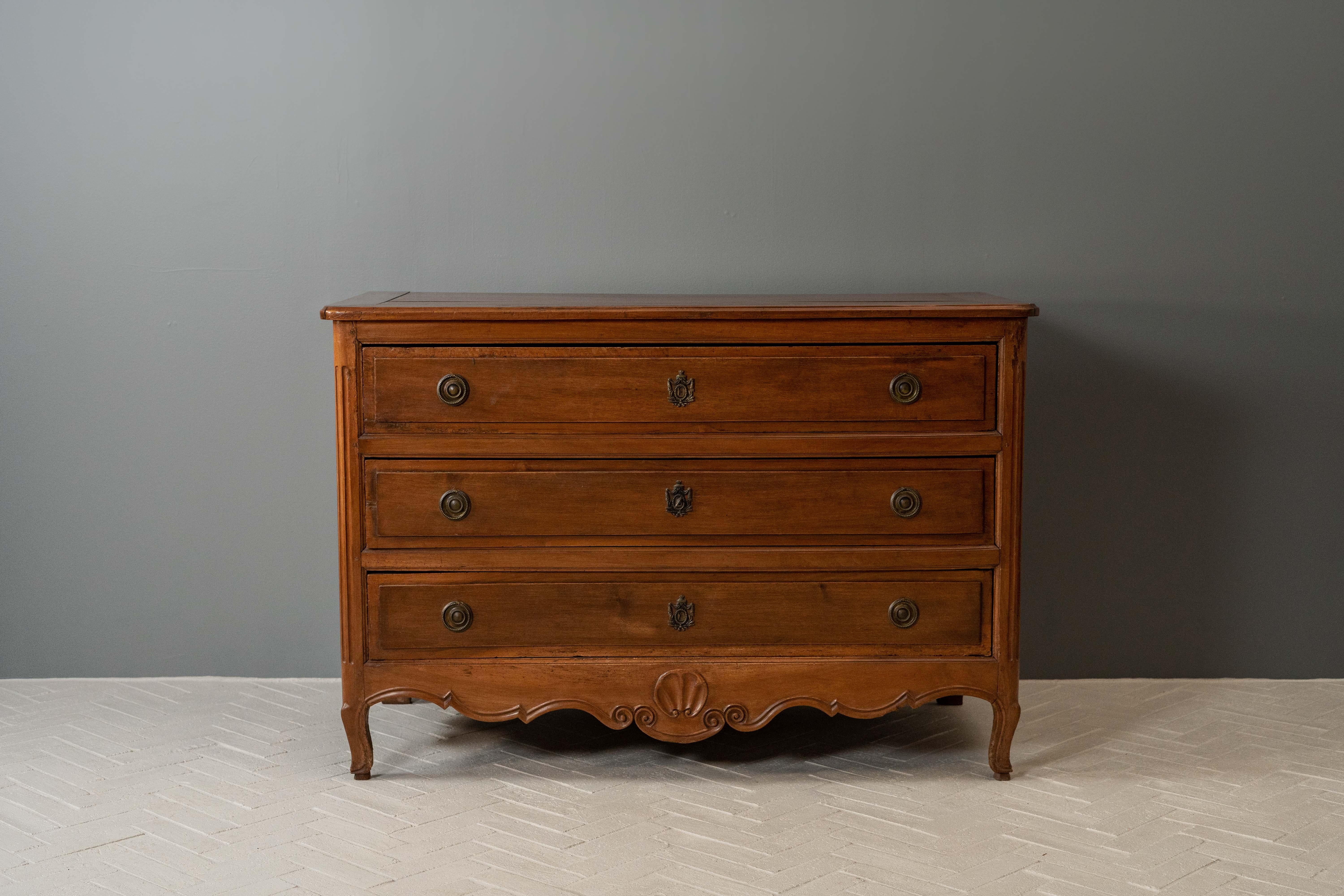 France, vers le XVIIIe siècle. Une charmante commode Louis XV datant probablement de la fin des années 1700. Ce meuble en noyer incroyablement robuste comporte trois grands tiroirs, chacun doté de poignées et d'écussons en bronze. Le tablier