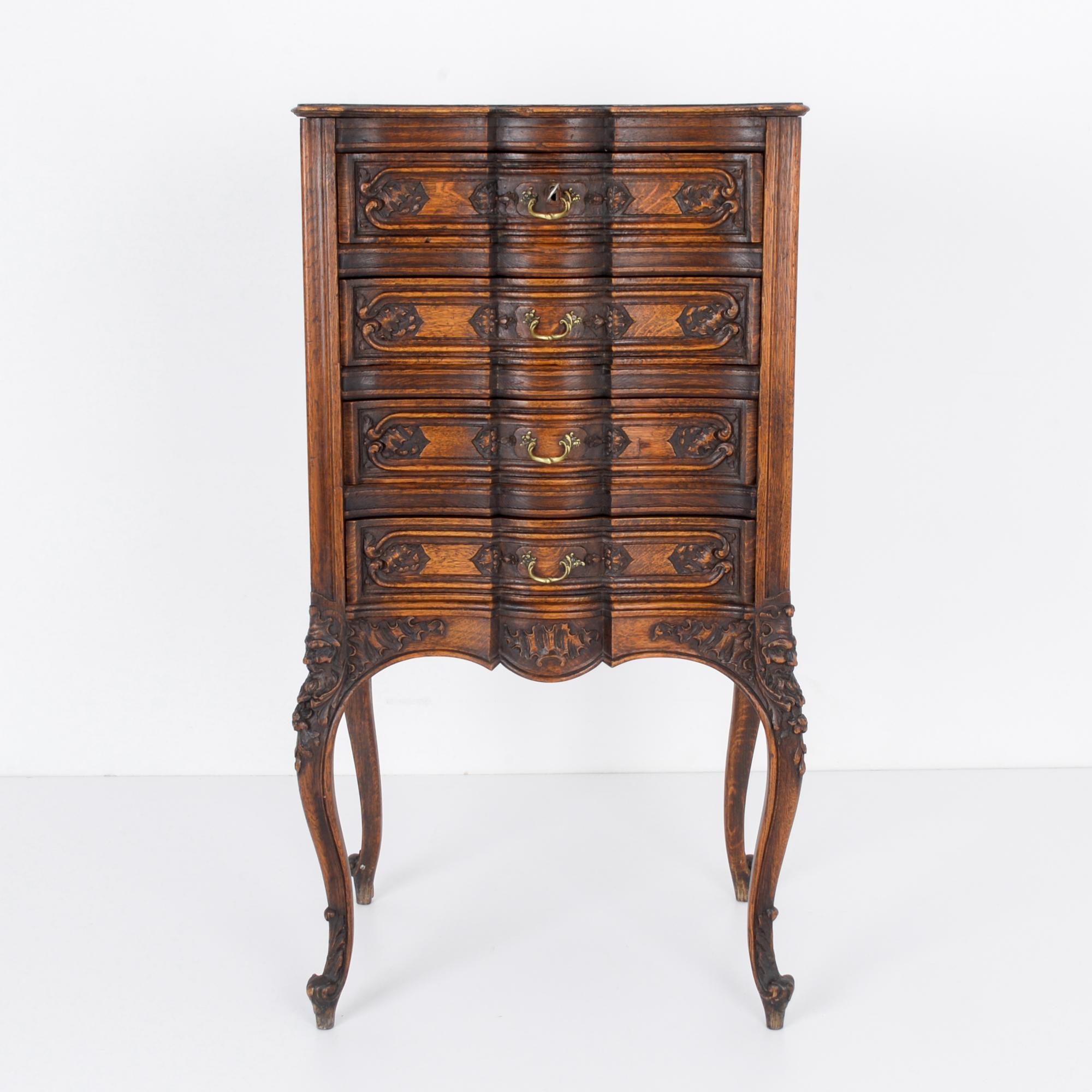 This ornate wooden chest of drawers with intricate carvings of leaves, flowers, and faces was made in France. Elevated on cabriole legs, the center of the drawers are carved to have a recessed appearance. The elegant paneling and contoured apron