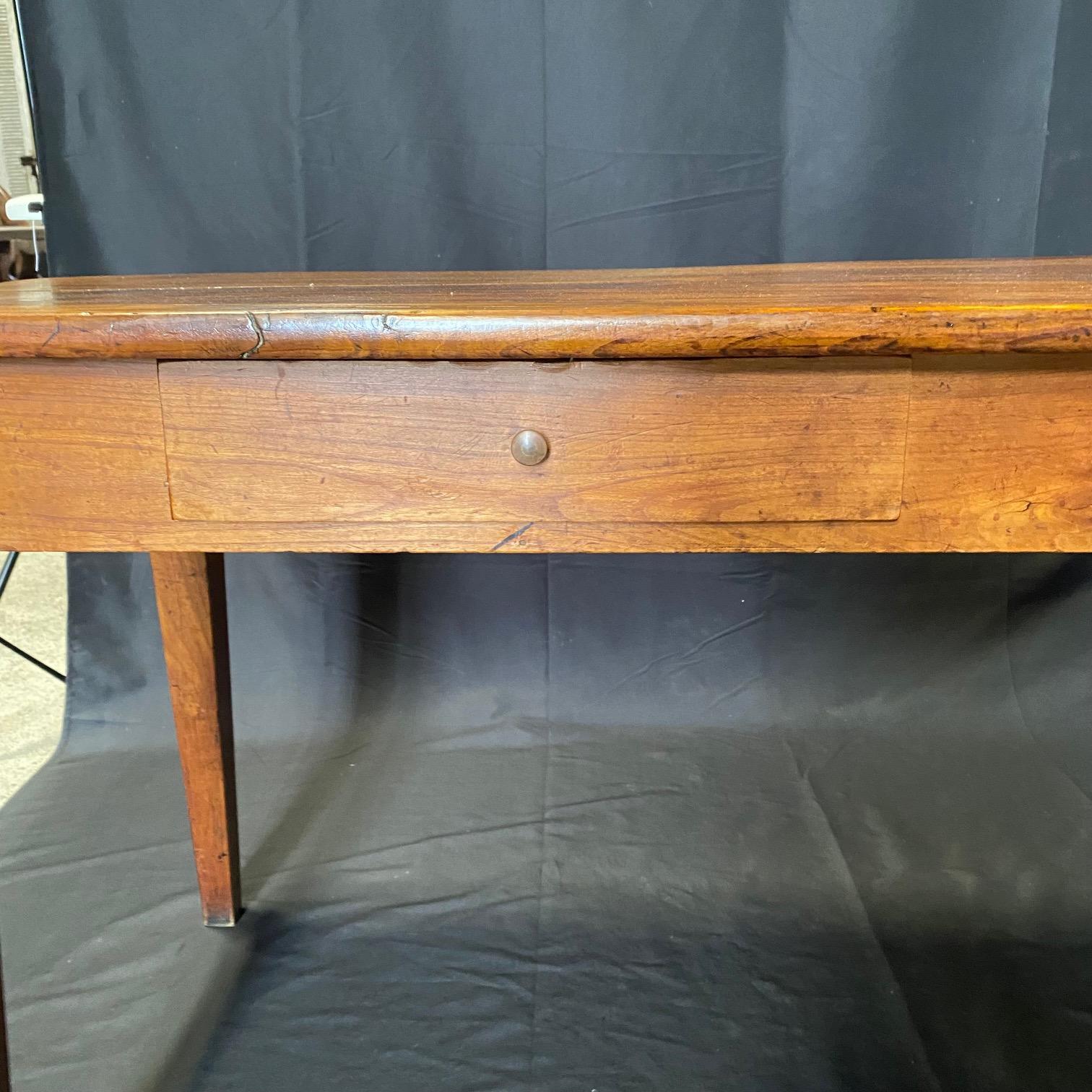 Elegant charming French cherry dining table from the 19th century. This exquisite antique French dining table is a timeless treasure that offers both functionality and elegance. With two drawers, this dining table provides ample storage space for