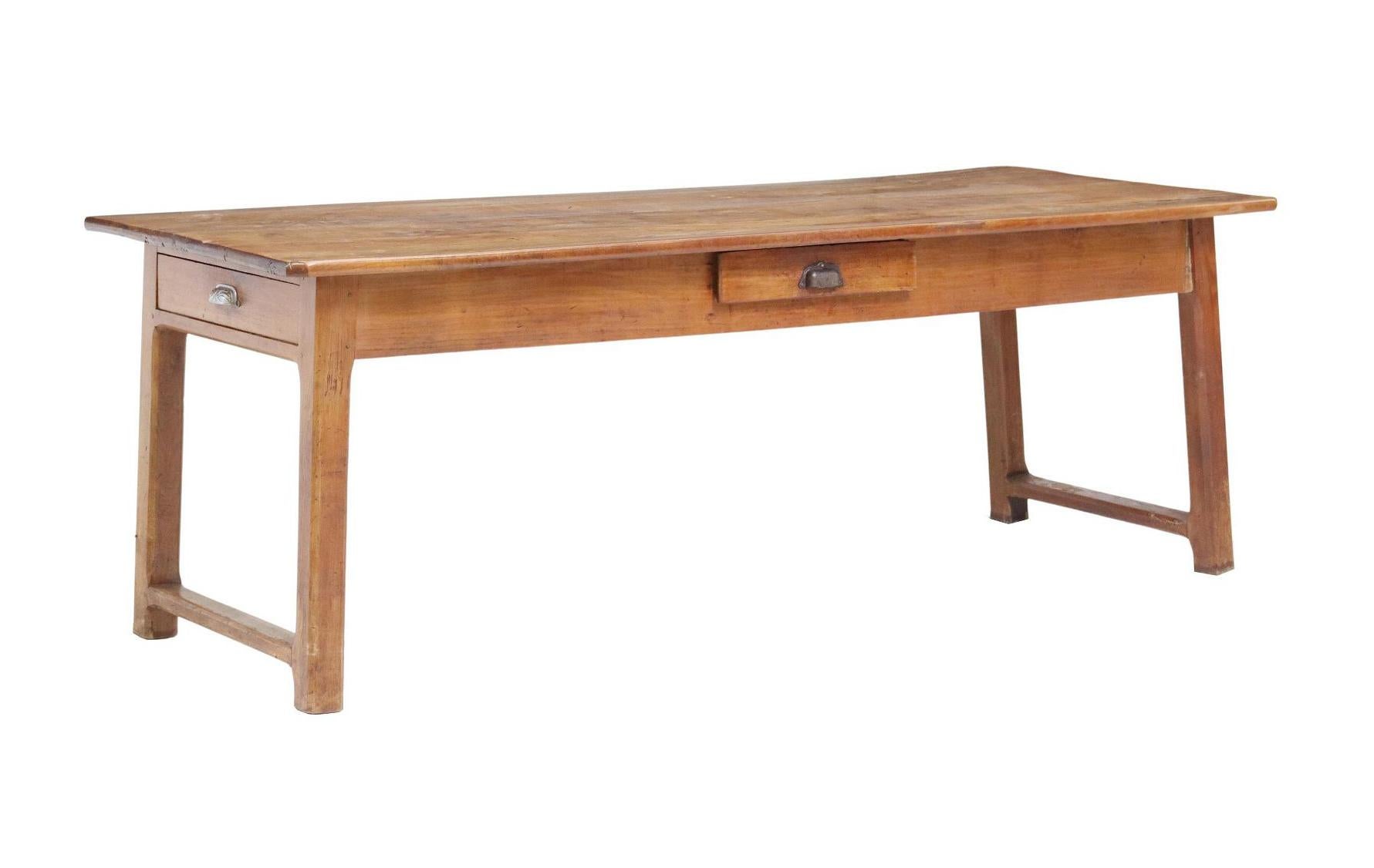 Ancienne table de ferme provinciale en bois fruitier, C.I.C.. Le plateau de table est composé de quatre planches. La table comporte deux tiroirs en frise, repose sur des pieds joints par étirement, une séparation et un remplissage entre les planches