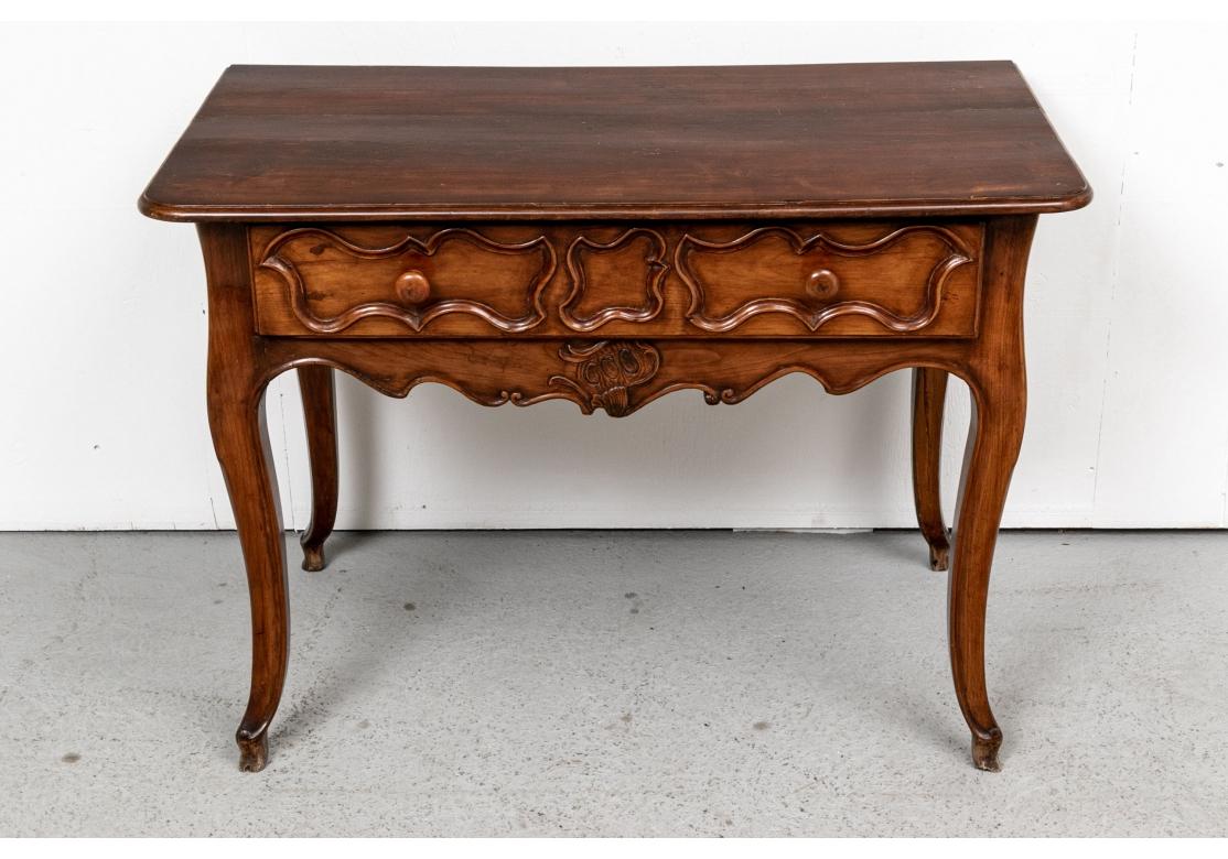 A plank constructed overhanging top over a long drawer with raised carved cartouche moldings and knob pulls. The serpentine apron with carved complimentary cartouche motif on front. The tall cabriole legs with carved stylized hoof feet. 
L. 41