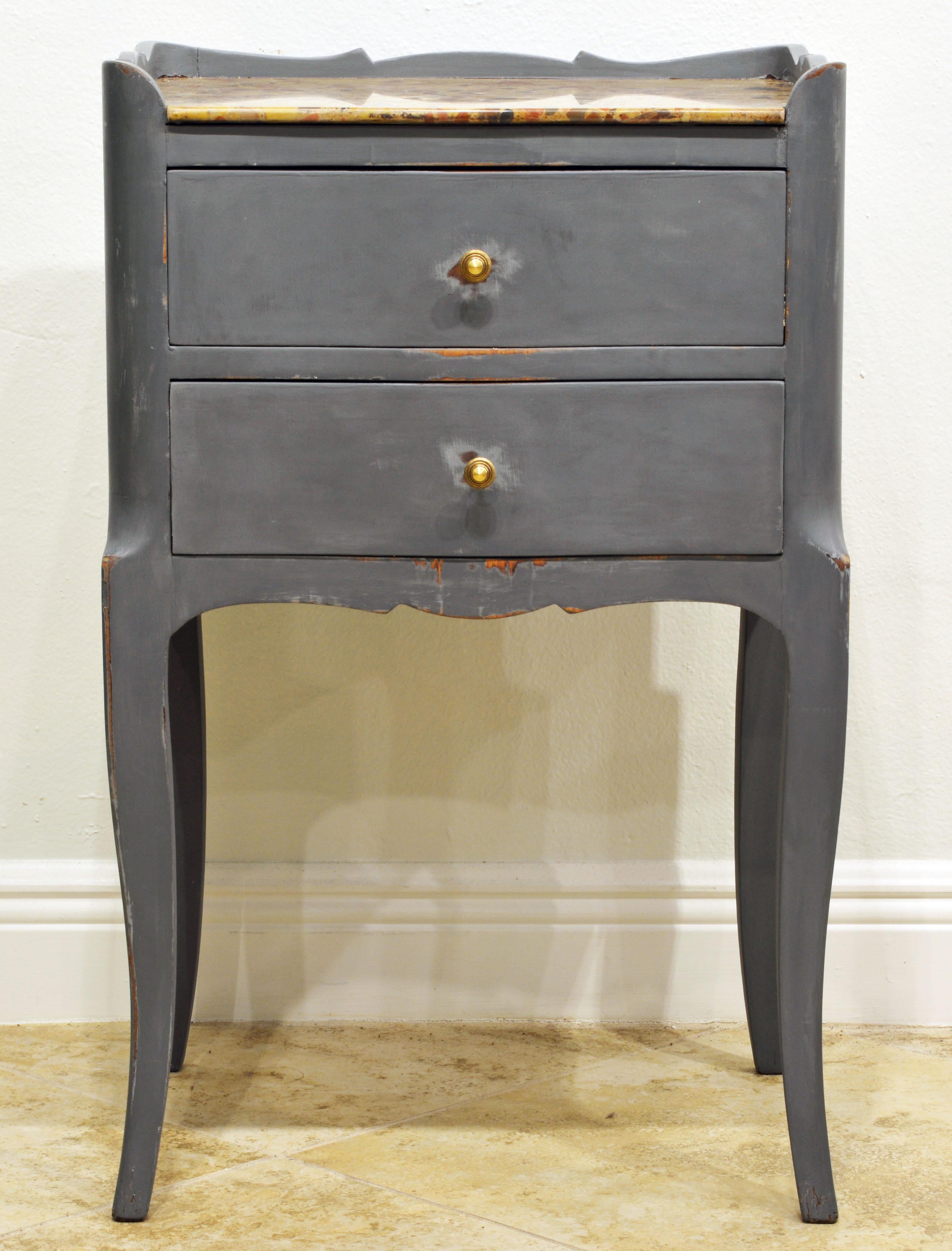 This commode likely dates to the end of the 19th century or the early 20th century. It features a polychrome marble top surrounded on three sides by a scalloped edge above two drawers and resting on elegant cabriole legs. At a later time painted