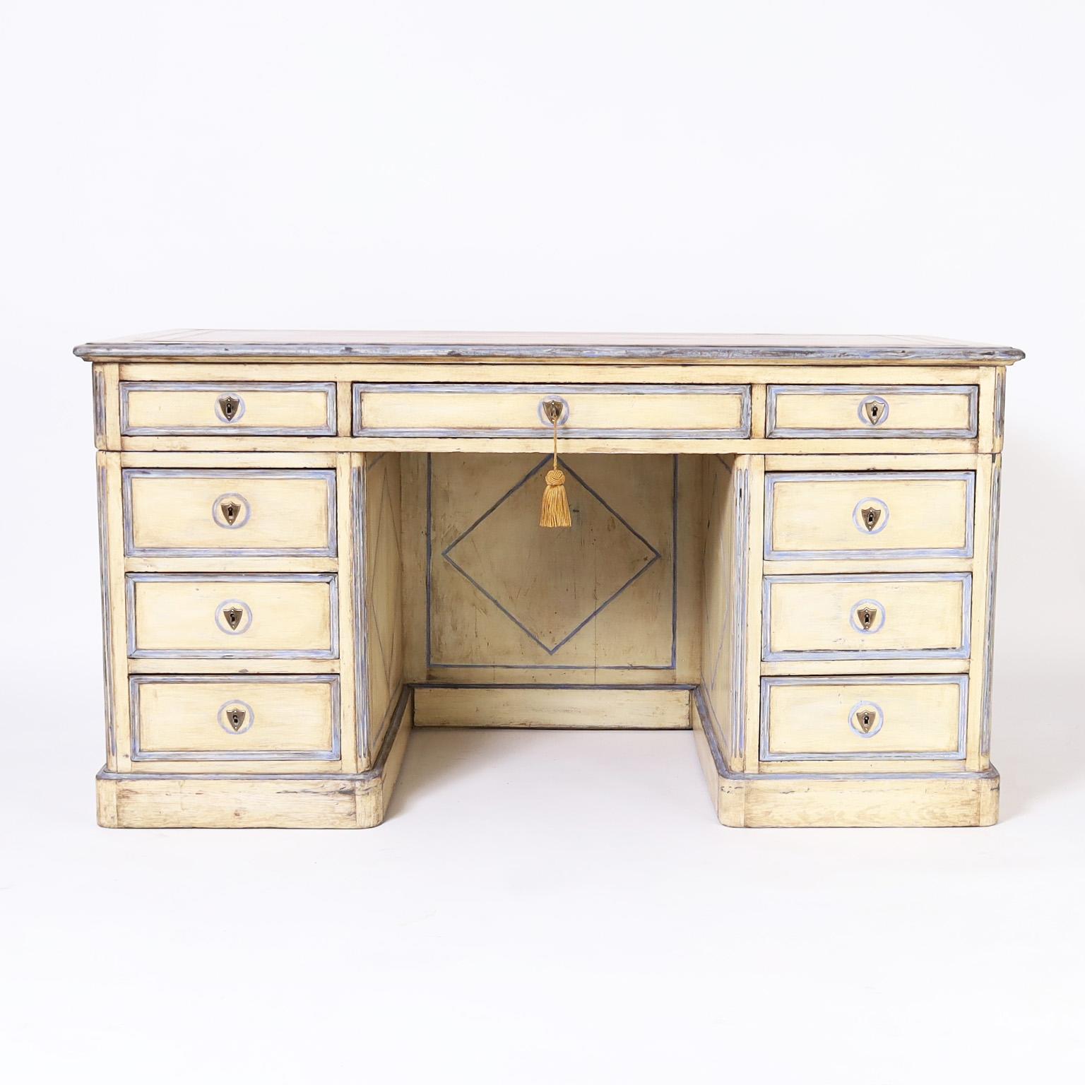 Dynamic 19th century kneehole desk with a brown tooled leather top over a three piece pedestal base with nine drawers and two pullout trays retaining the original yellow and blue paint with geometric and greek key motifs.