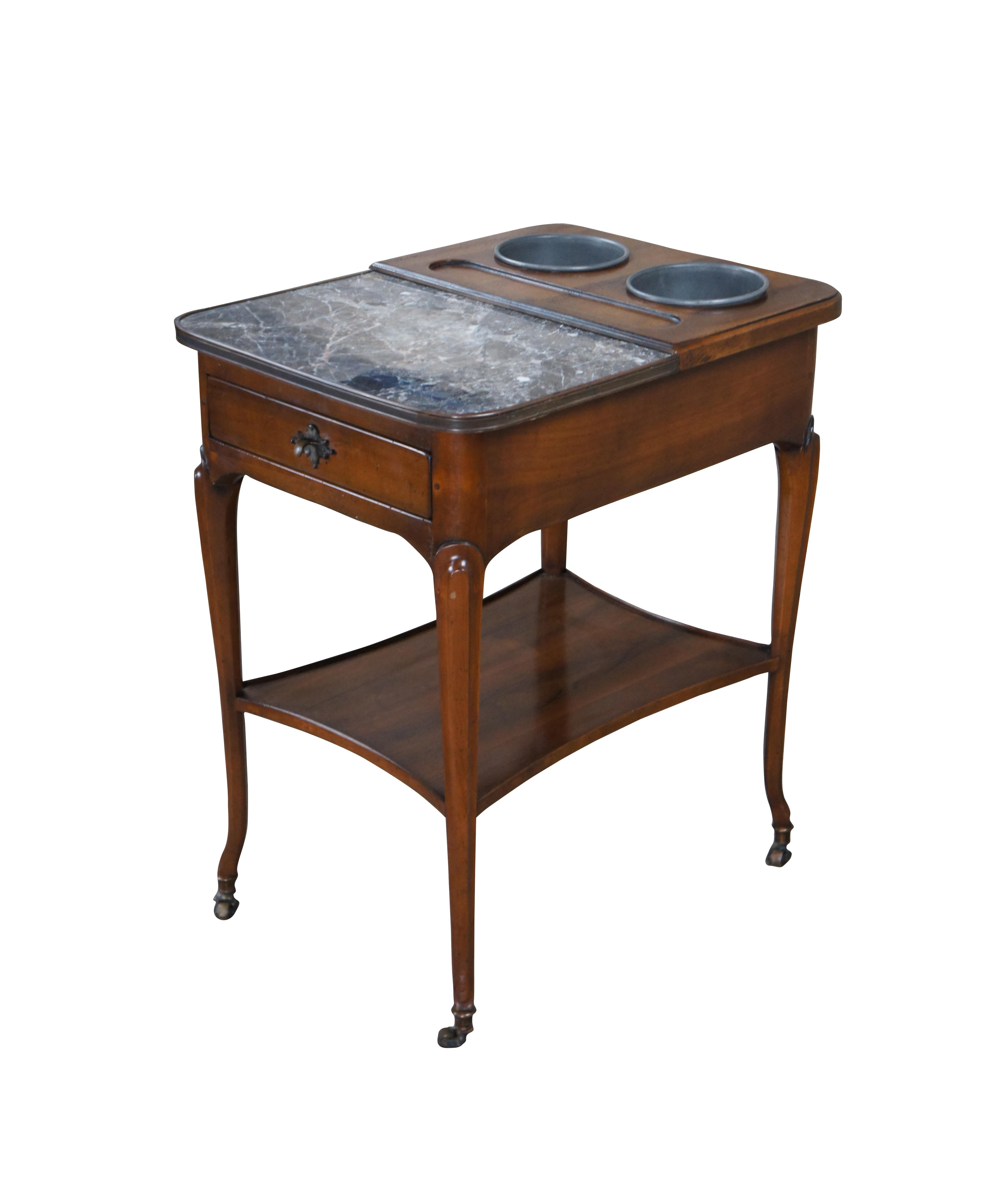 Exceptional Rafraichissoir Wine / Champagne Cooler Table in Cherry and Walnut, circa 1930s

Features a marble tray top and ingot mold with two metal cooler buckets. Includes a central drawer with bronze pull, long tapered legs, arched feet with