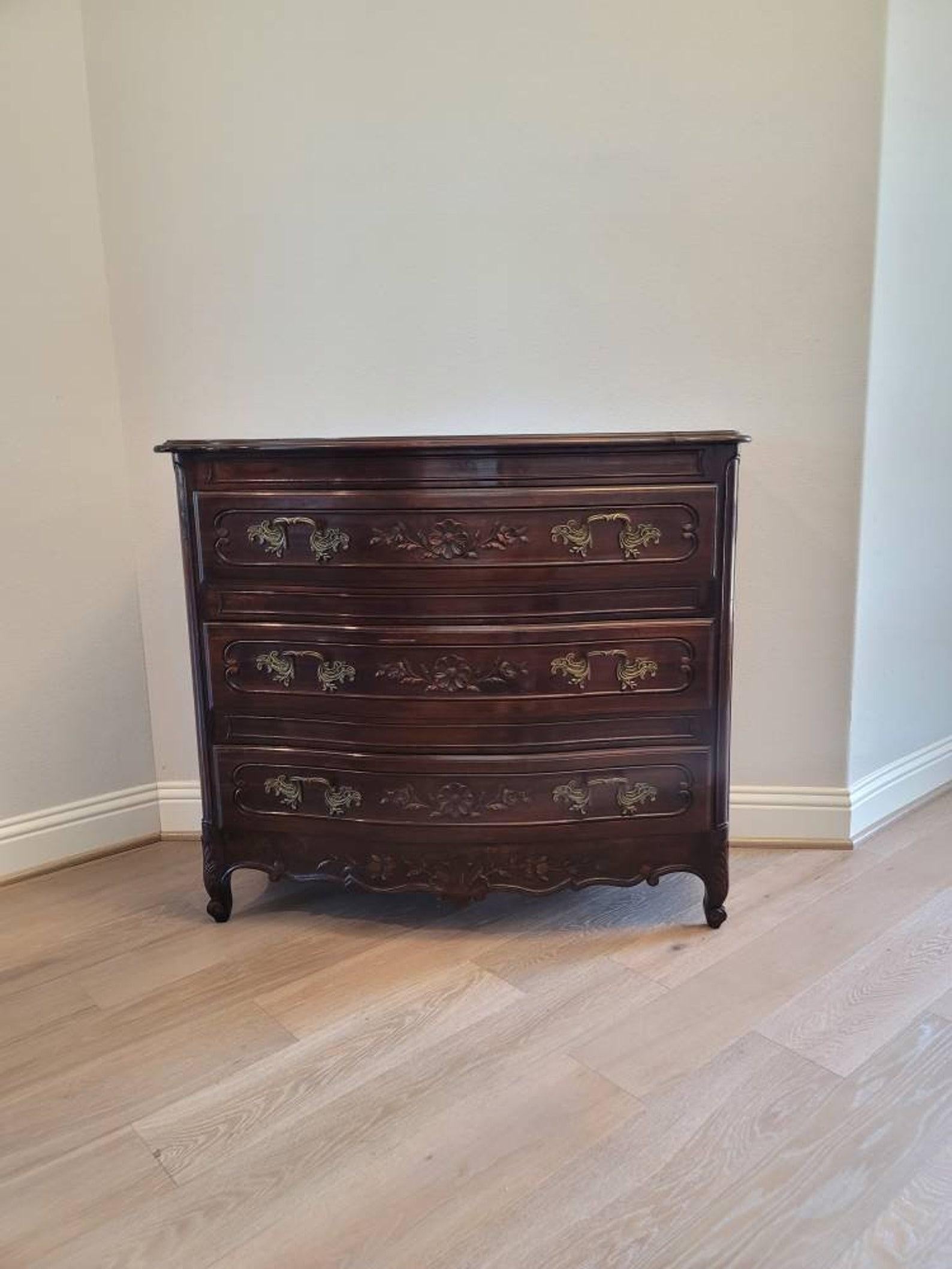 A fine French Provincial Louis XV style chest of drawers commode, early 20th century, having a serpentine shaped wooden top with molded edge, over conforming high quality solid wood case fitted with three drawers, each with dovetail joinery, ornate