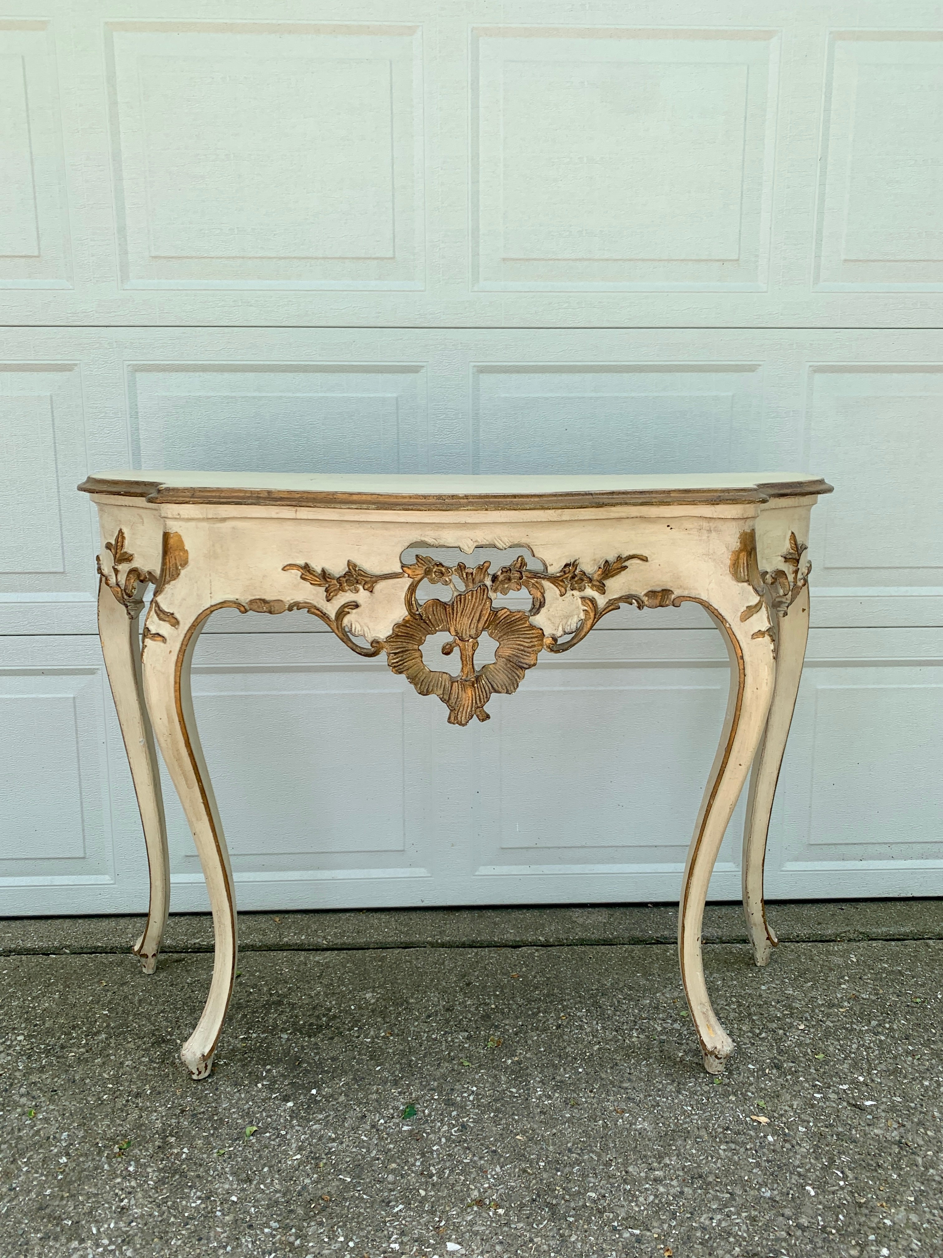 A gorgeous antique French Provincial Louis XV style console table

France, Early 20th century

Painted wood in a lovely antique cream color, with mounted gold gilt painted details, and a custom made glass top.

Measures: 43.75?W x 16.63?D x
