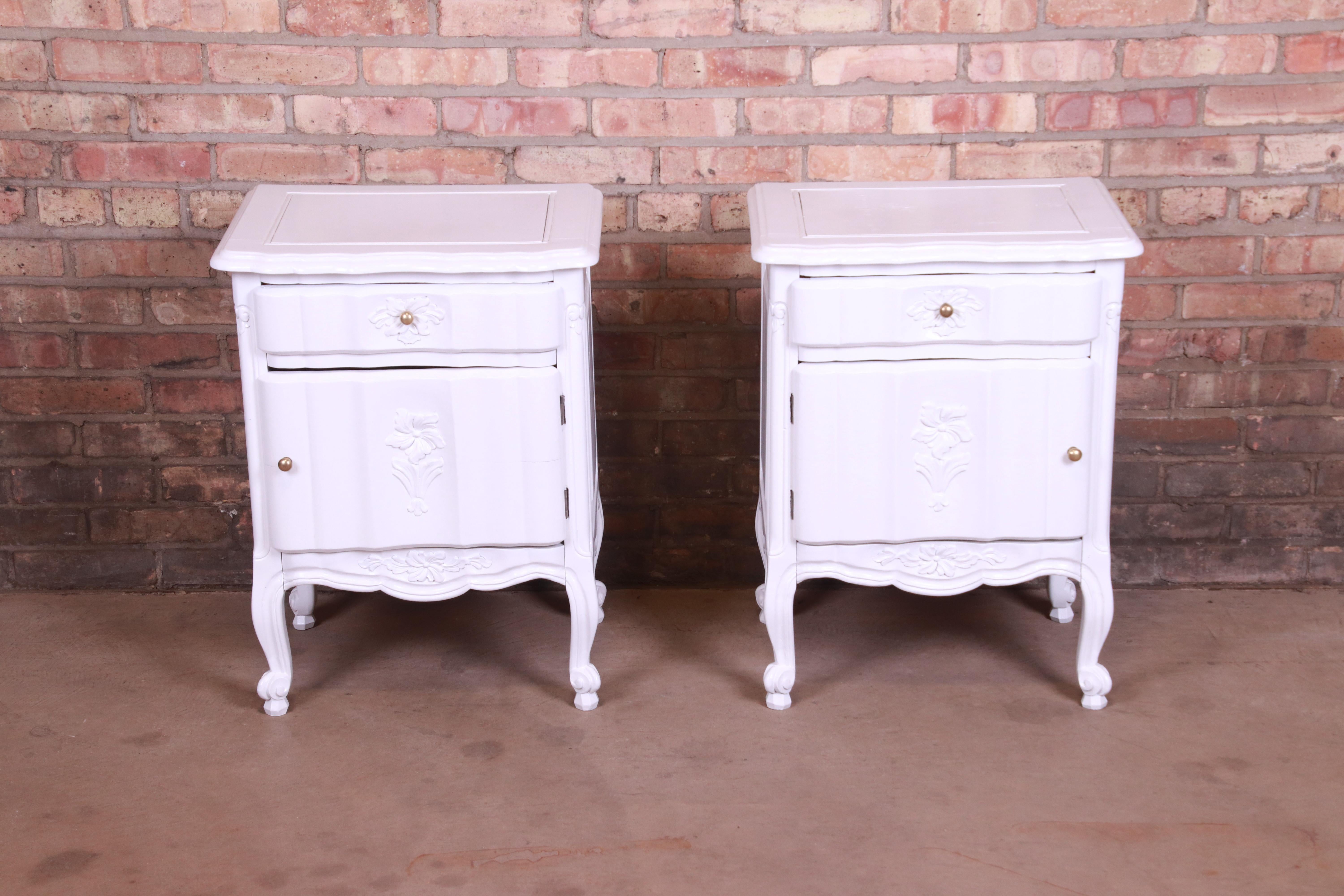 A gorgeous pair of antique French Provincial Louis XV nightstands

Circa 1920s

Carved white lacquered wood, with floral details and brass hardware.

Measures: 19.88