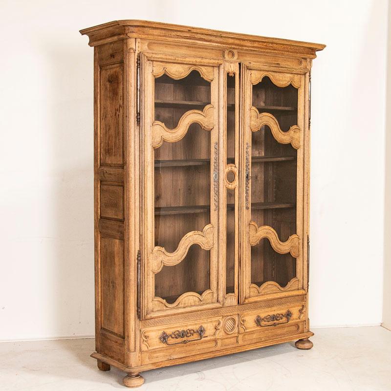 Striking in person, the beautiful details in this oak cabinet reminds one of the classic beauty found in French country style. Lovely carved details, panels and hardware accentuate this bookcase. With adjustable shelving, it will also serve as an