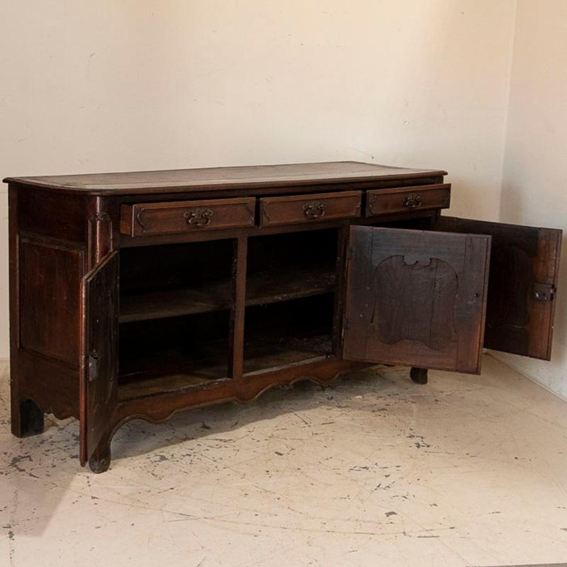 The beautiful walnut wood has aged gracefully, boasting a lovely rich patina in this French Provincial sideboard. Three drawers over three spacious lower cabinet doors allows for excellent storage as a dining room buffet among other uses. Notice the