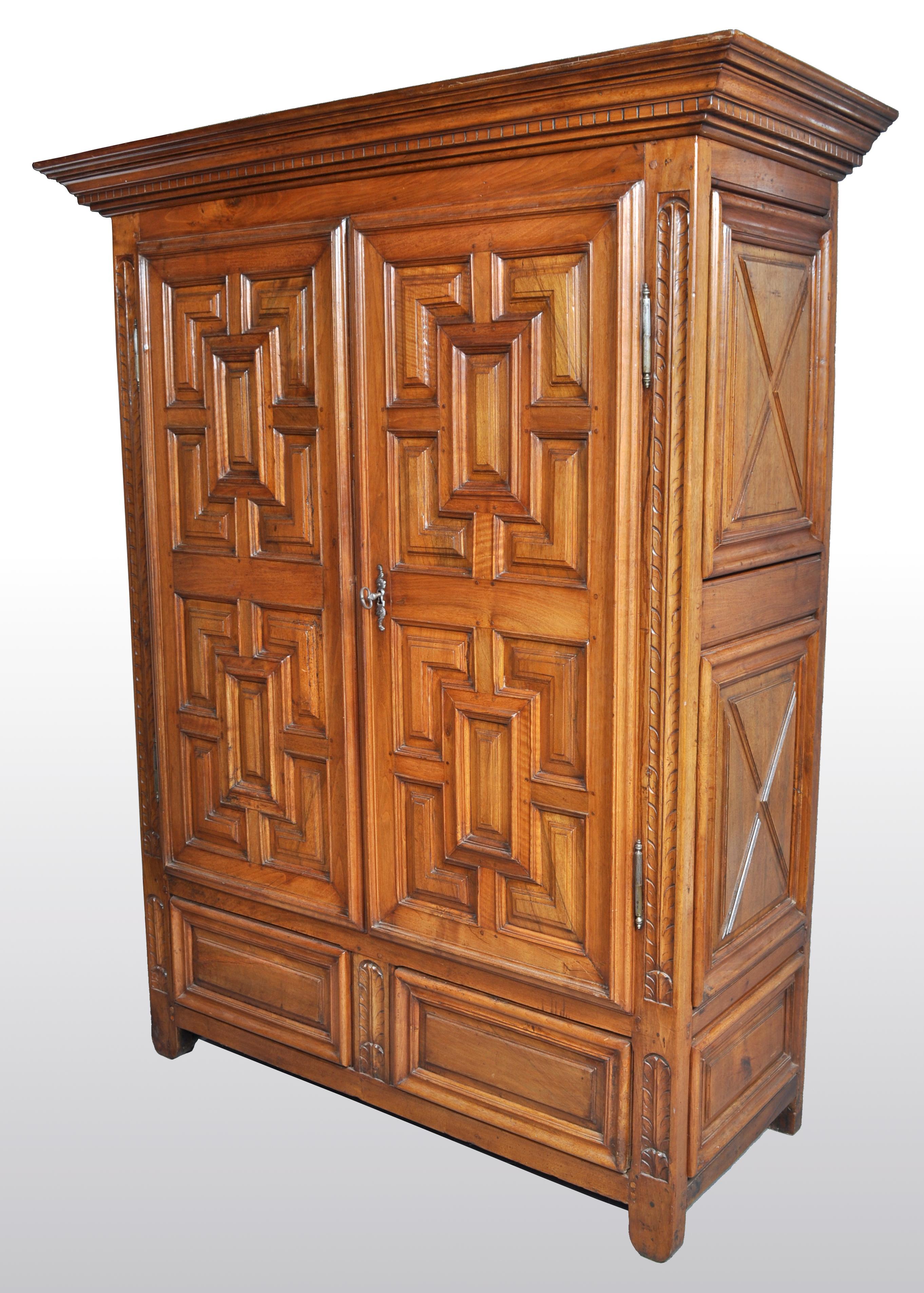 Antique French Provincial walnut armoire / cabinet, circa 1750. The armoire having a stepped cornice above a gallery of dentil molding, below a pair of panel doors having deeply carved geometric decoration and flanked by a pair of carved acanthus