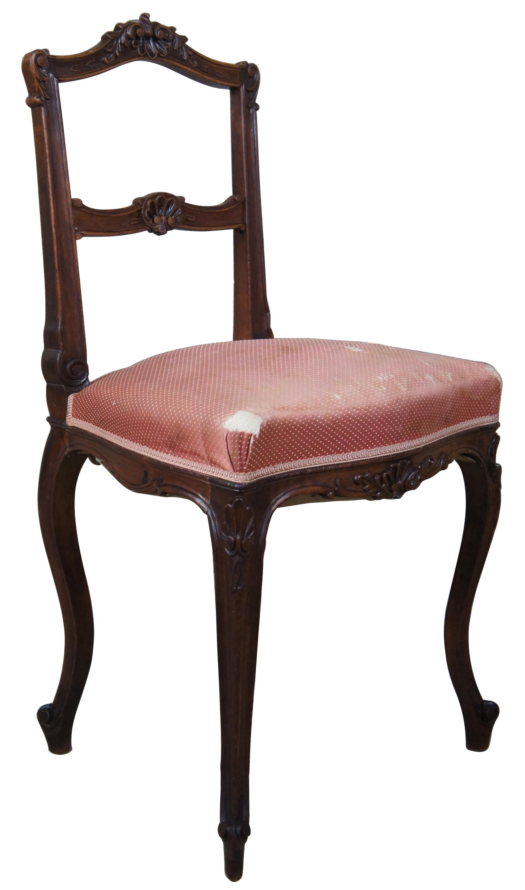 Antique French Provincial side chair. Made from walnut with ornate shell and cartouche carvings. Features a pink upholstery over cabriole legs and scrolled deet.
  
