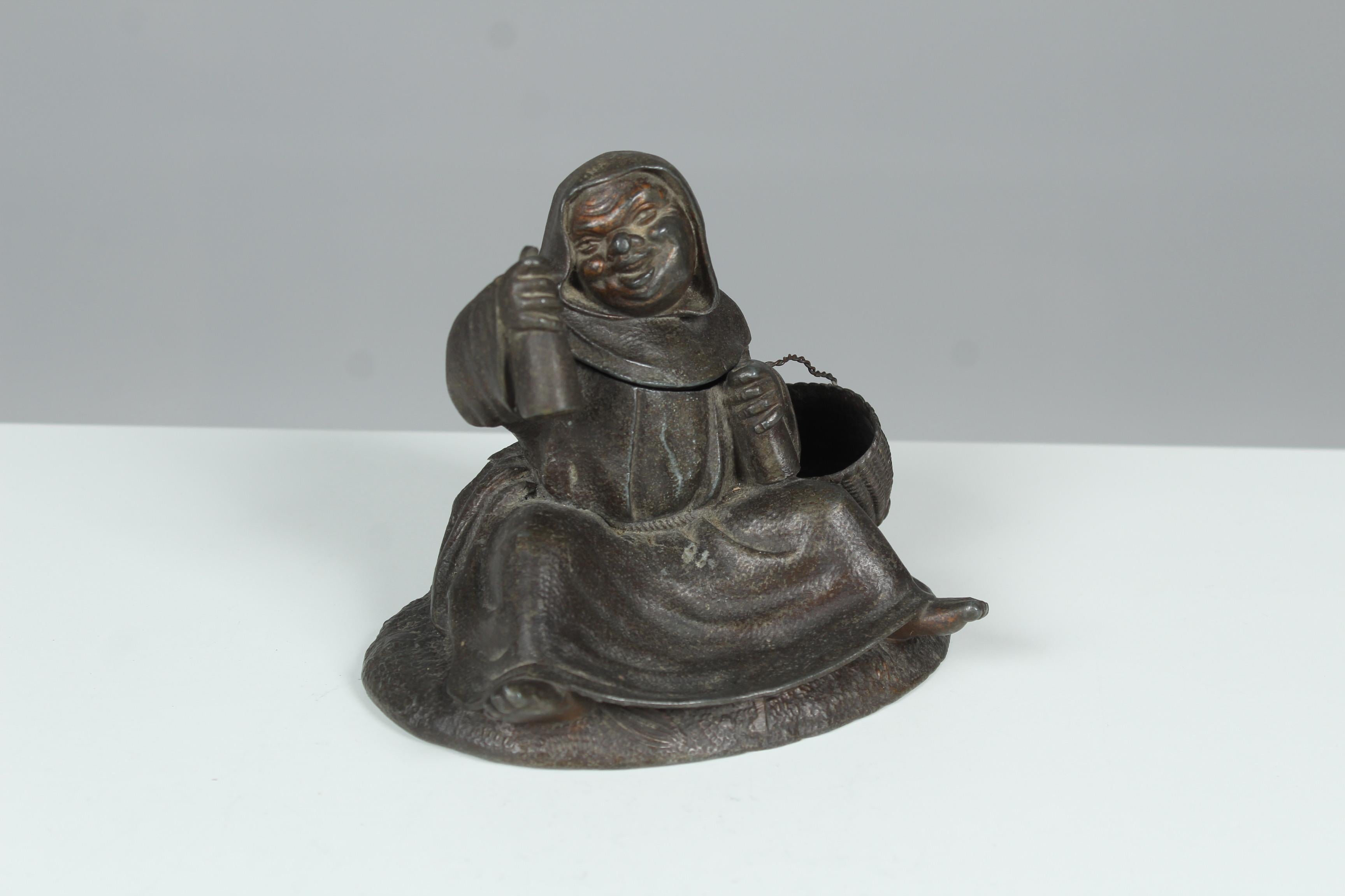 Seltene Skulptur eines fröhlichen Mönchs mit einem Geheimfach.
Ein so genanntes Pyrogene, das für Rauchutensilien wie Streichhölzer verwendet wurde.
Der Mönch hält zwei Flaschen in den Händen und hebt einen Arm, um mit der Flasche anzustoßen.
Der