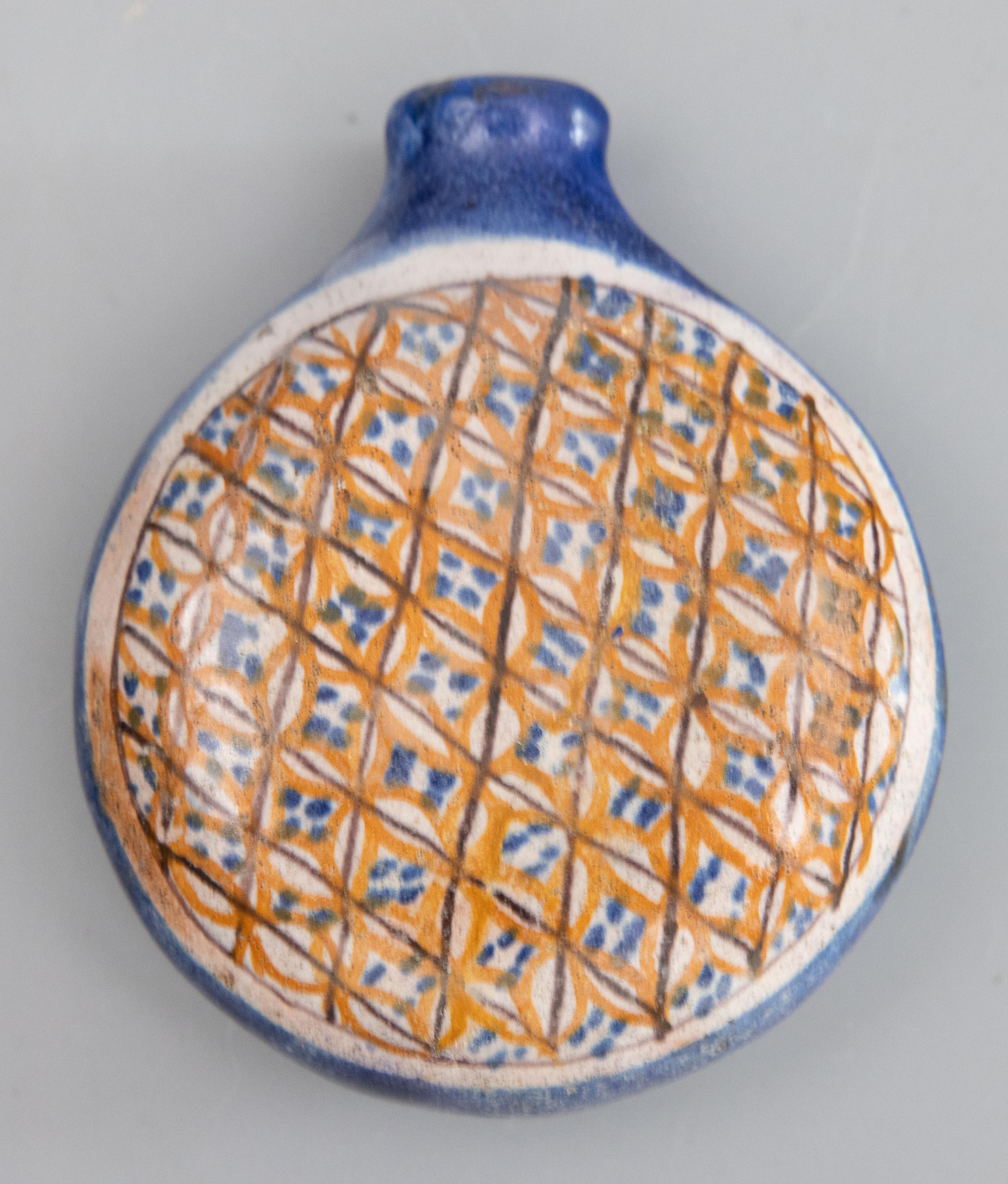 Un joli flacon rond et plat en faïence de Quimper, peint à la main par des artisans français. Il s'agit d'un rare flacon de tabac à priser daté de 1900, très intéressant pour la collection, avec un motif de guirlande florale sur une face et un motif
