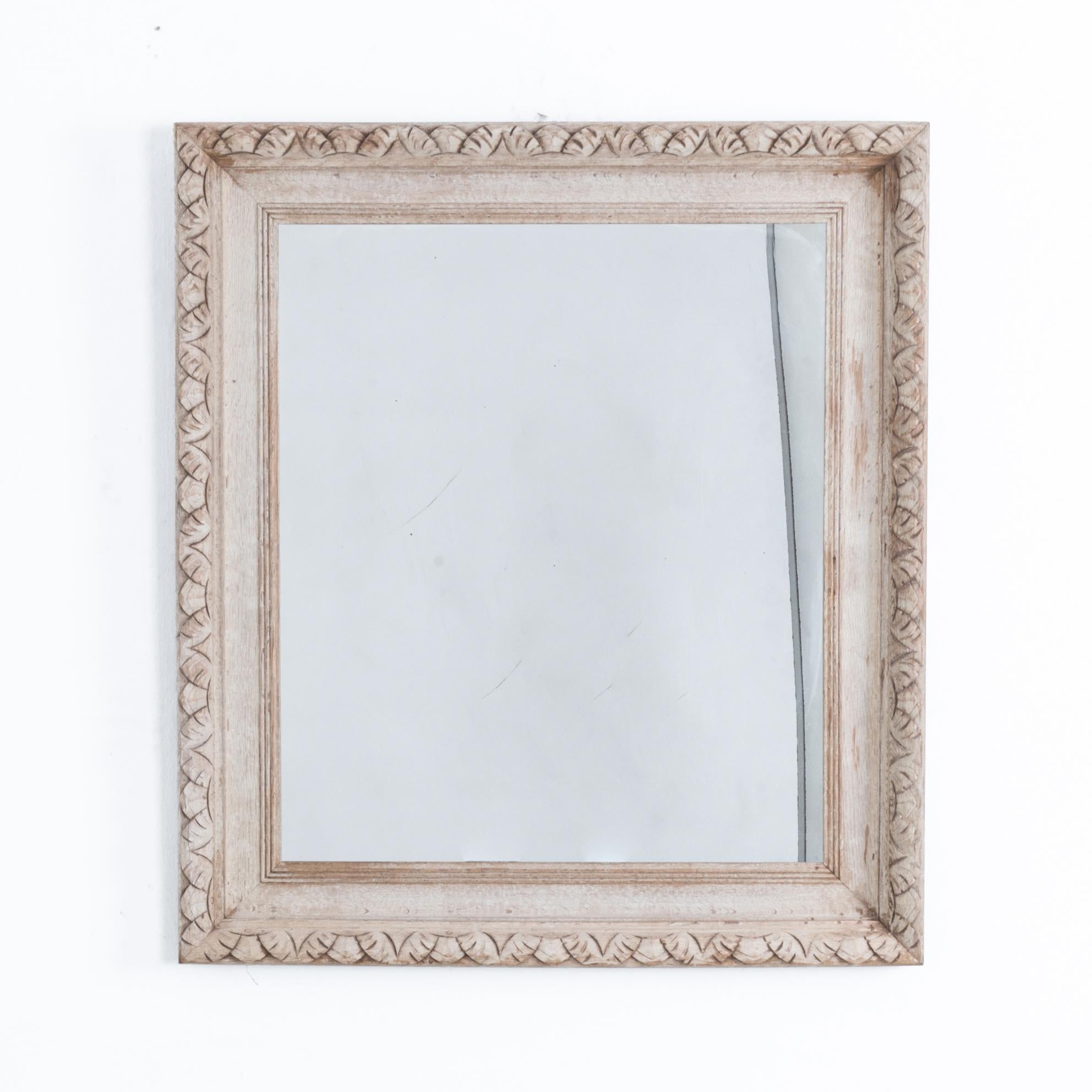 An elegant mirror frame from France circa 1900. An echo from the past, this mirror blends grounded symmetry with intricately carved wooden decoration. Carved leaf patterns recall a classical beauty, elevating simple geometry. Updated in our atelier