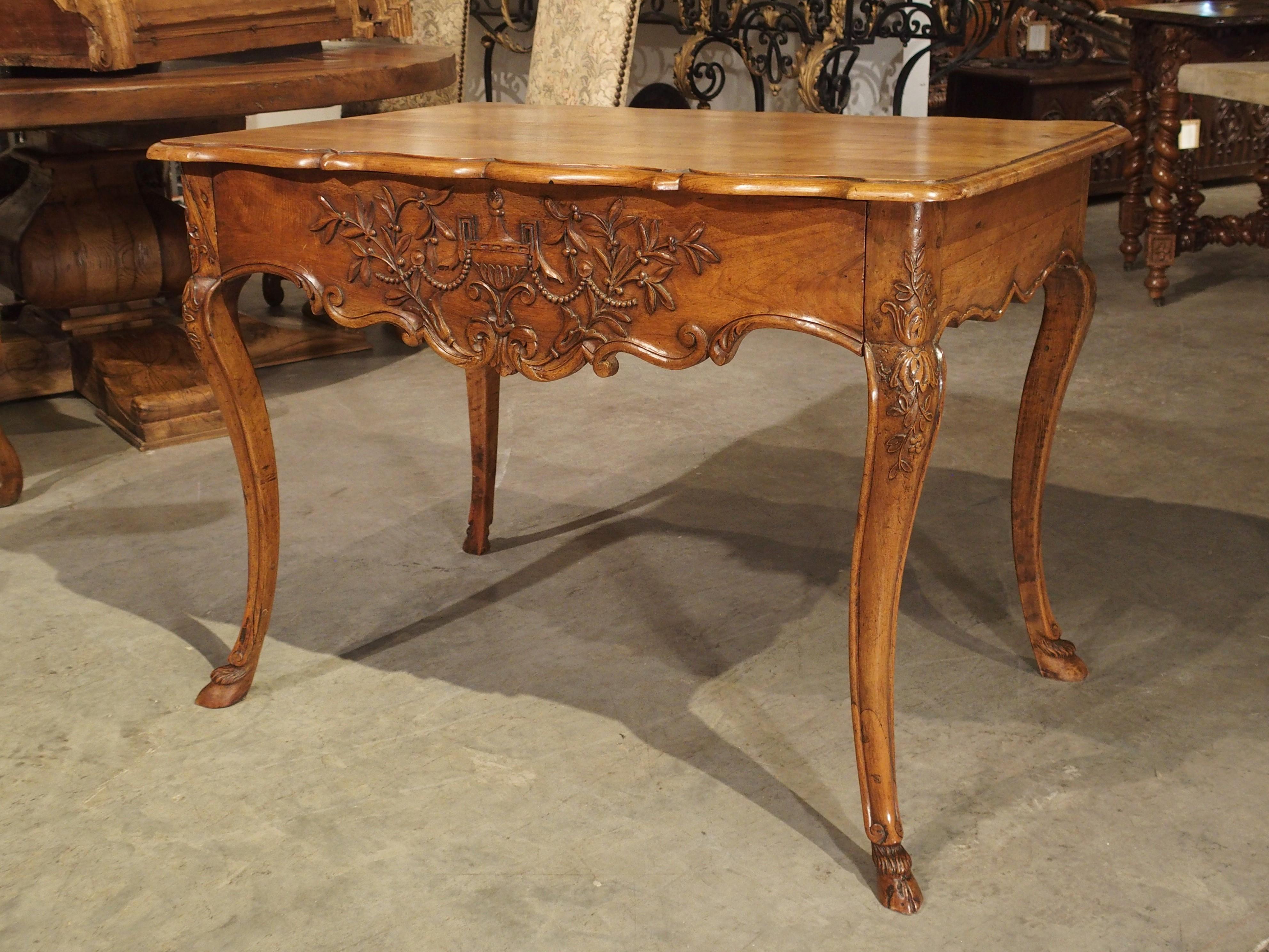 There are some delicate and unique features to this Regence style walnut wood console table from France, circa 1860. It combines period design elements, with a thoughtful and discreet front drawer, and carved apron and top edges along the sides as