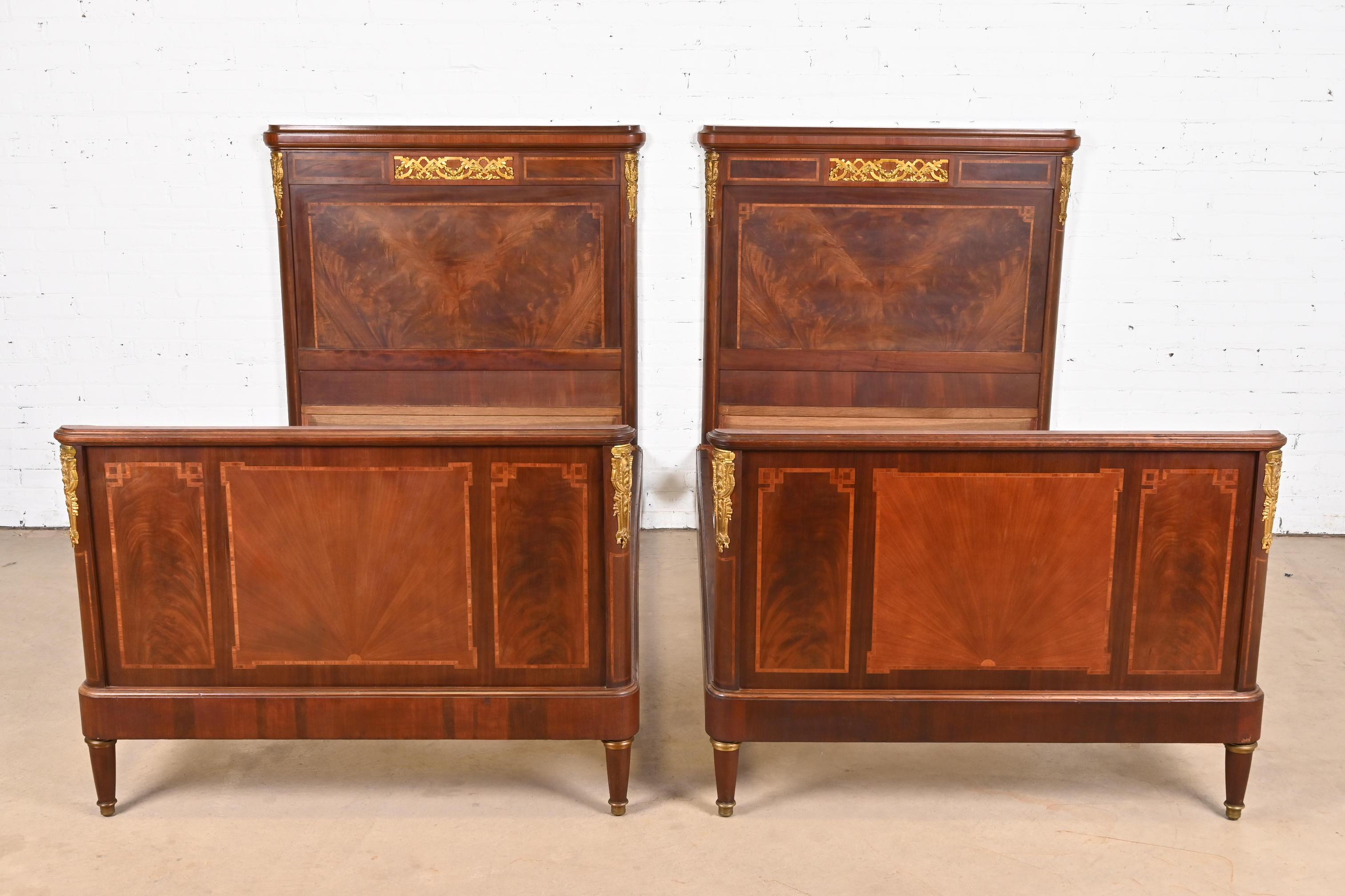 A gorgeous pair of antique French Empire, French Regency, or Louis XVI style twin size beds

France, Early 20th Century

Gorgeous book matched flame mahogany, with inlaid satinwood banding, and mounted gilt bronze ormolu.

Each measures: 44.25