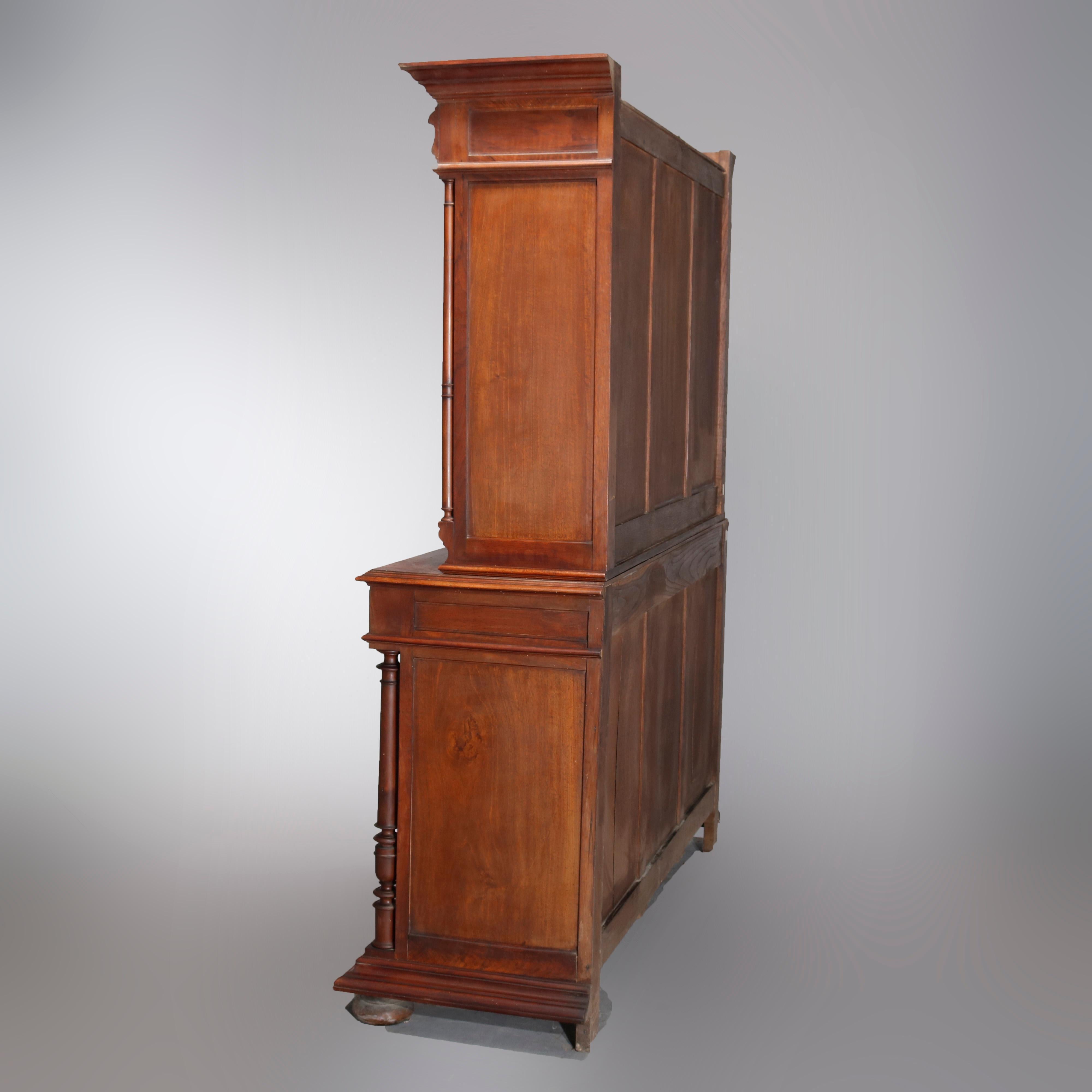 Antique French Renaissance carved mahogany step-back court cupboard with upper having triple paneled door flanked by full turned columns, surmounting lower with double reeded doors and double doors with geometric elements flanked by full turned
