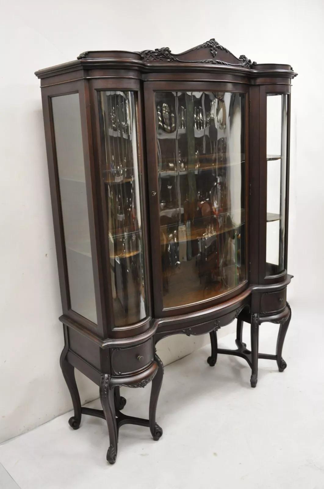 Antique French Renaissance Dark Walnut Triple Bowed Glass China Cabinet. Item features 2 lower drawers, raised on cabriole stretcher base legs, triple bowed glass, 2 wooden shelves, nice carvings throughout, working lock and key. Circa Early 20th