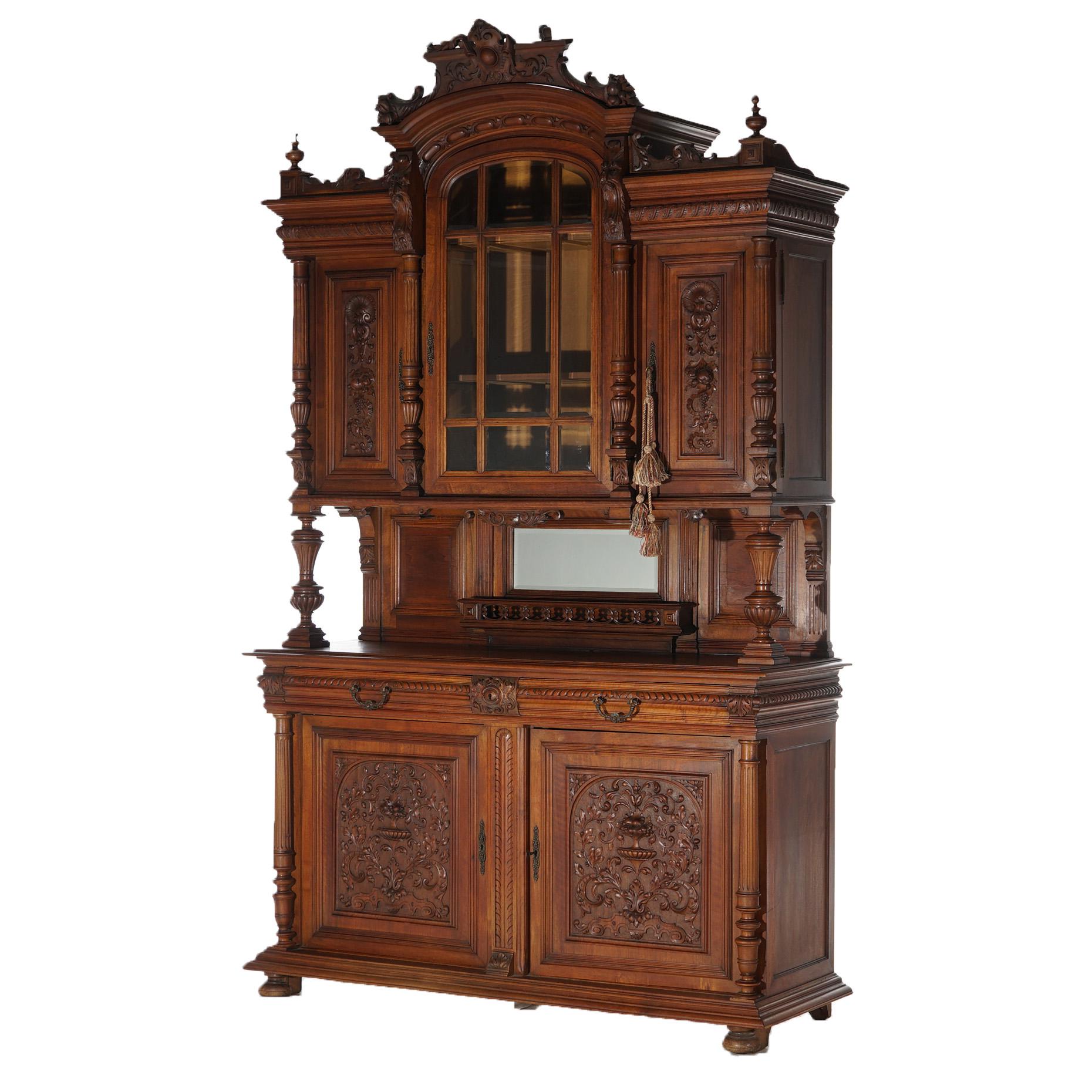 An antique figural French Renaissance hunt board server offers walnut construction with foliate carved pediment having central cartouche and flanking finials over upper case with three cabinets including central with paneled glass door; gallery with