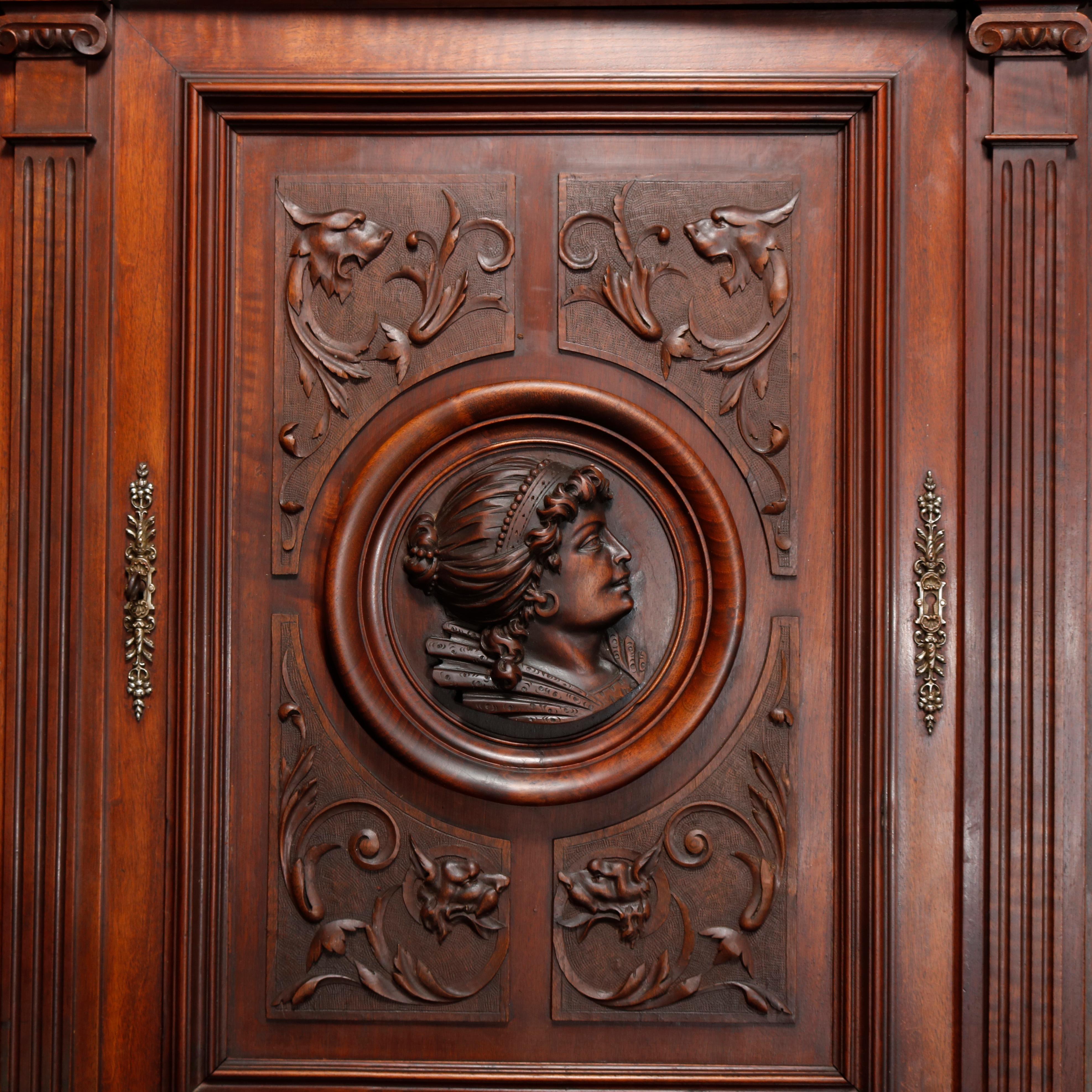 Antique French Renaissance carved walnut cabinet with upper having central door with mask and flanked by foliate carved doors, surmounting double drawer and double door lower with broken arch architectural elements, raised on bun feet, 19th