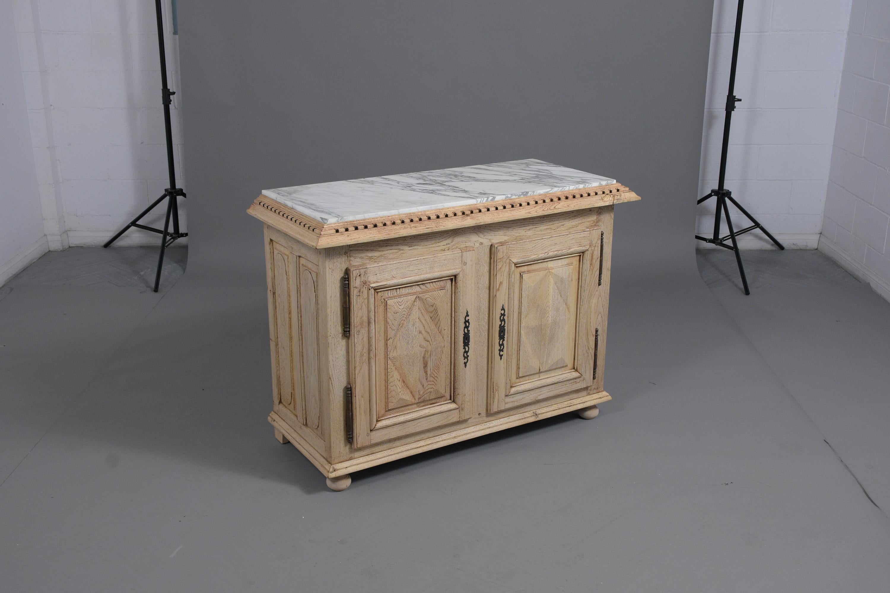 A beautiful 19th-century French buffet hand-crafted out of oak wood with a newly bleached finish and has been professionally restored. This 1890's server features a white Carrera marble top with gray vines framed with carved molding, the bottom has