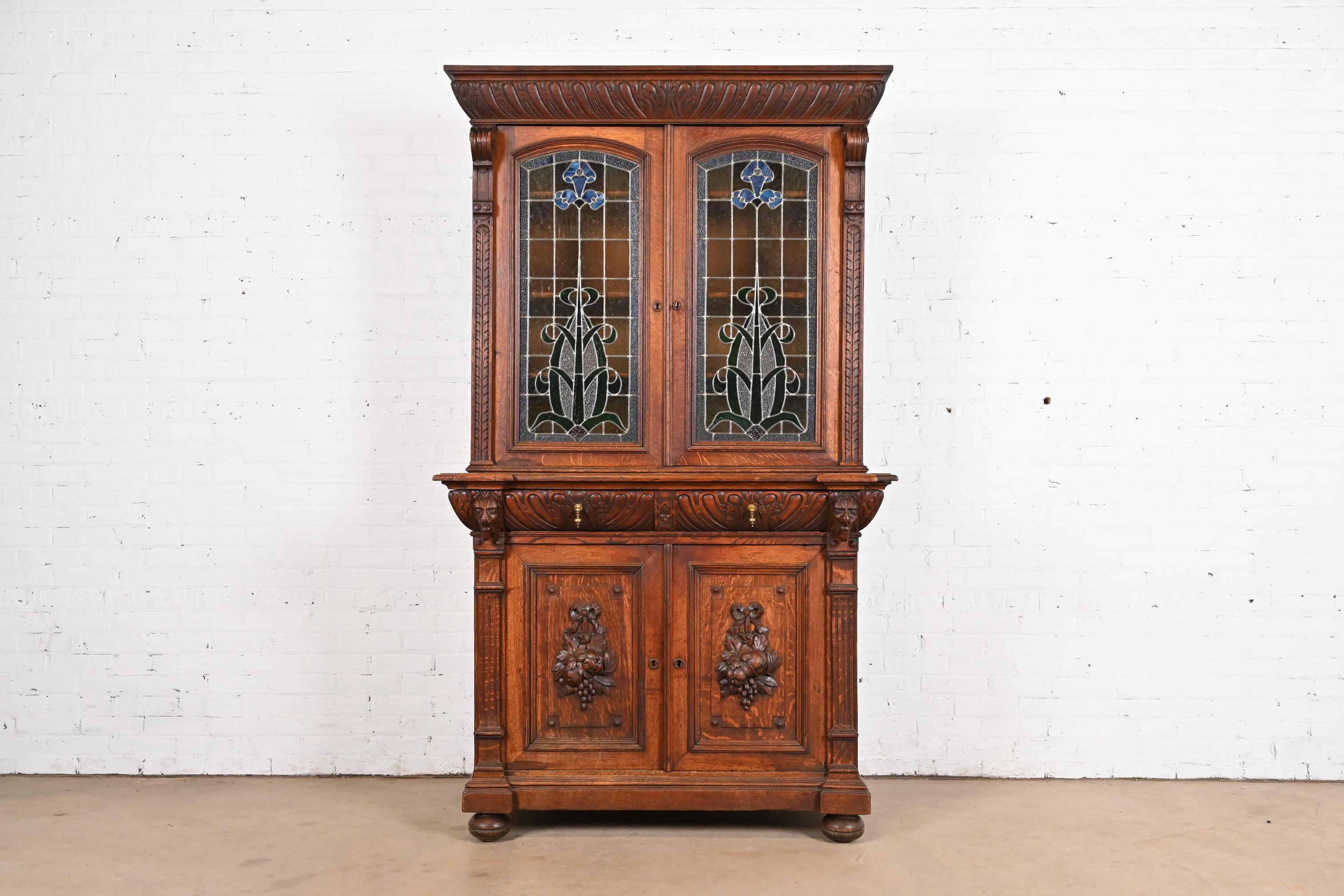 A gorgeous antique French Renaissance Revival breakfront bookcase, cupboard, or bar cabinet 

In the manner of R.J. Horner & Co.

France, Circa Late 19th Century

Ornate carved oak, with lion heads, beautiful stained leaded glass doors, and brass