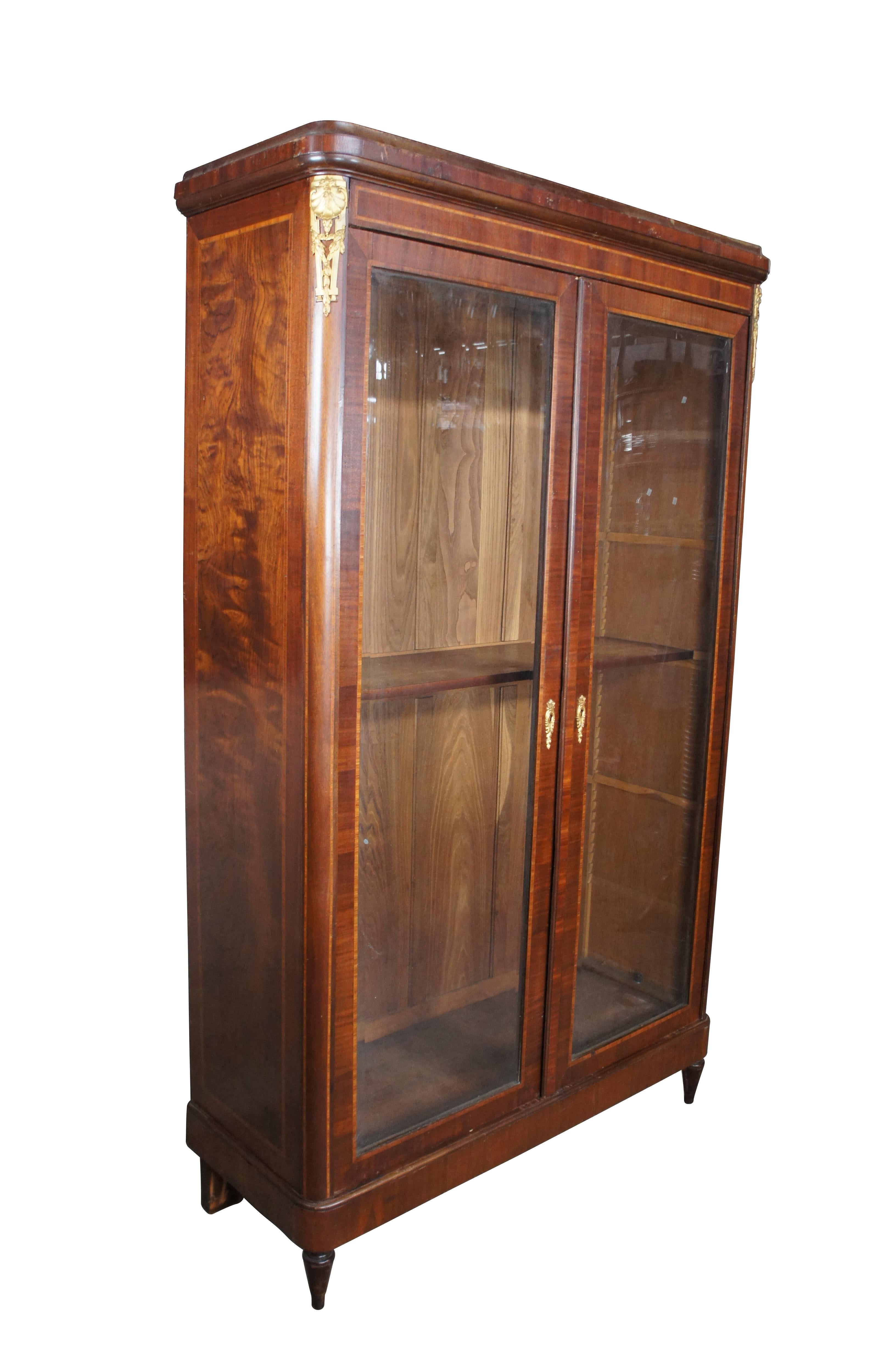 A very large and impressive antique French Renaissance Revival knockdown bookcase / showcase / curio display cabinet / or linen press.  Made of flame mahogany featuring gilt ormalu mounts, inlaid cross banding, large beveled glass doors and tapered