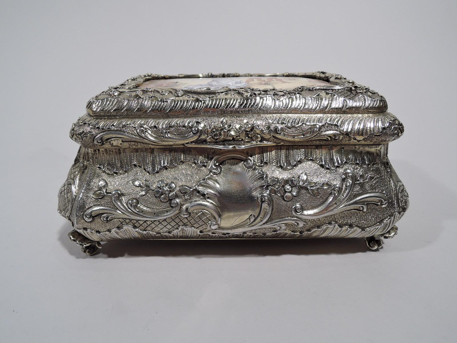 French gilt 950 silver casket, circa 1900. Bombe with chased scrolls and flowers on granulated and diaper ground. On front, asymmetrical cartouche (vacant). Four scrolled corner supports. Cover hinged and raised and inset with enamel plaque