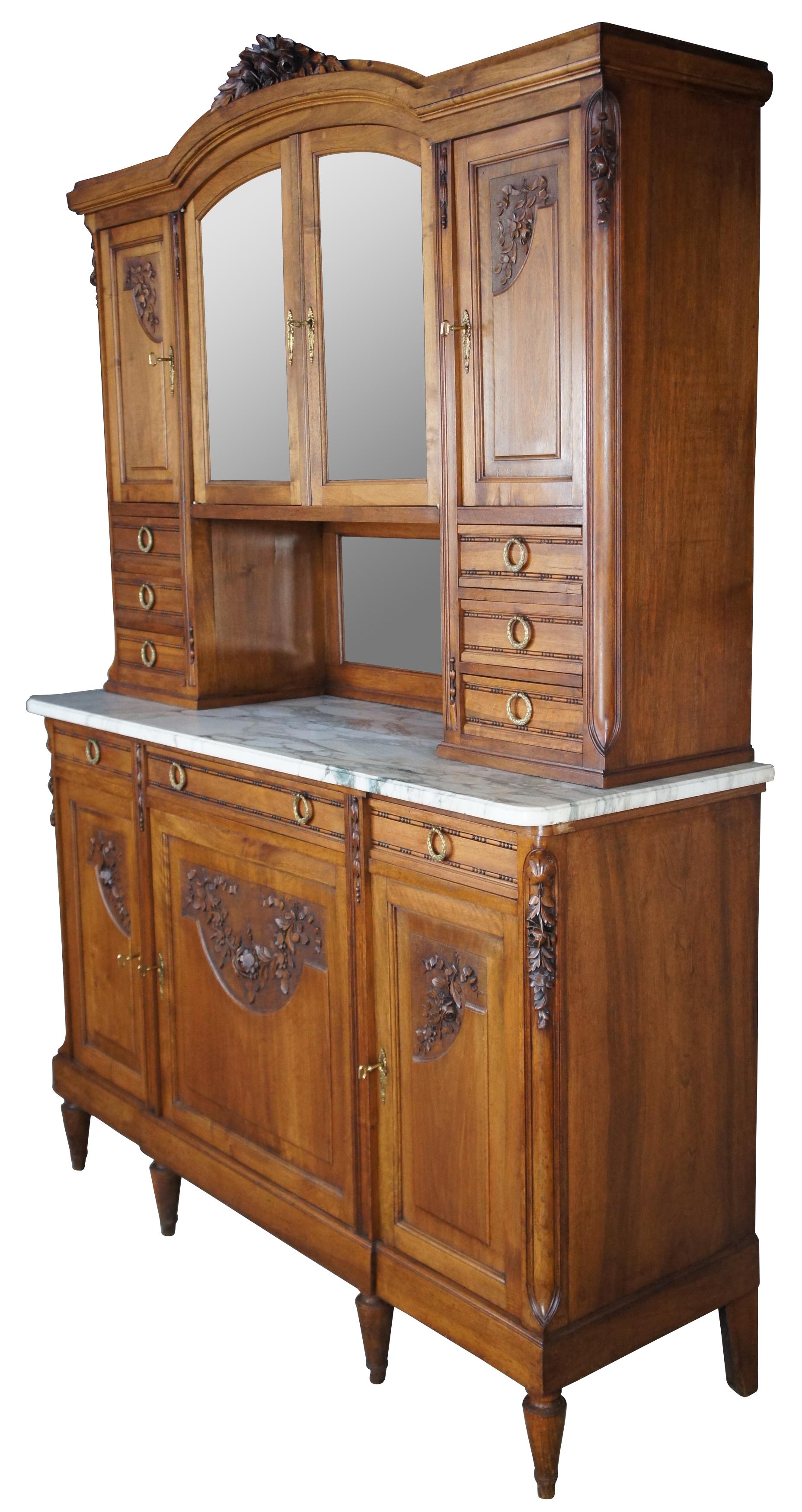 Antique Victorian era French Renaissance Huntboard, circa 1890s. Made from walnut with beautiful foliate hand carvings, a white marble top and intricate mirrored hutch. Buffet portion features three drawers with beaded carving and neoclassical brass