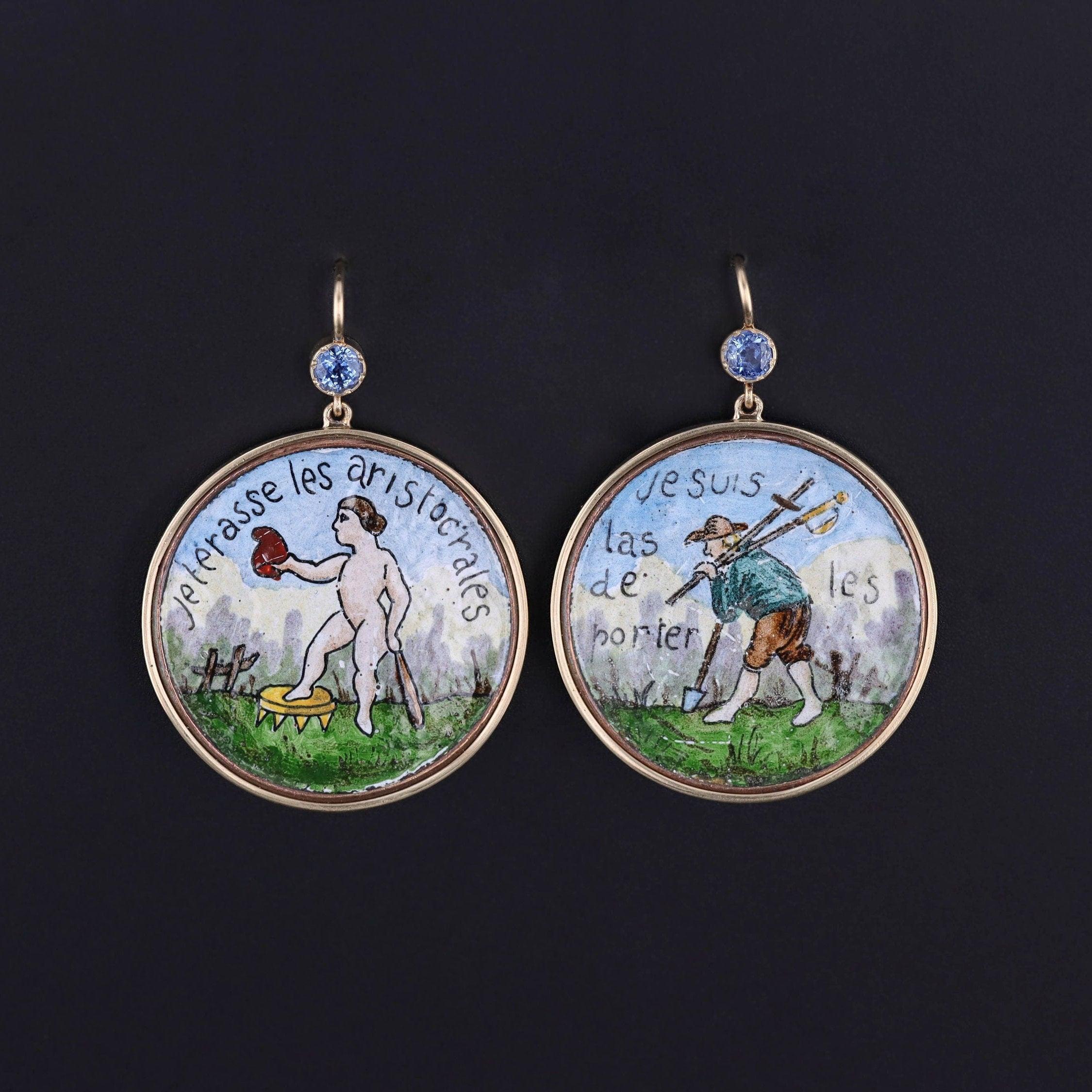 An extraordinary pair of earrings created from very rare buttons dating to the time of the French Revolution (1789-1799).

The earrings are hand painted enamel. One bears a person stepping on a crown with a bat and squeezing a heart in his hand. It