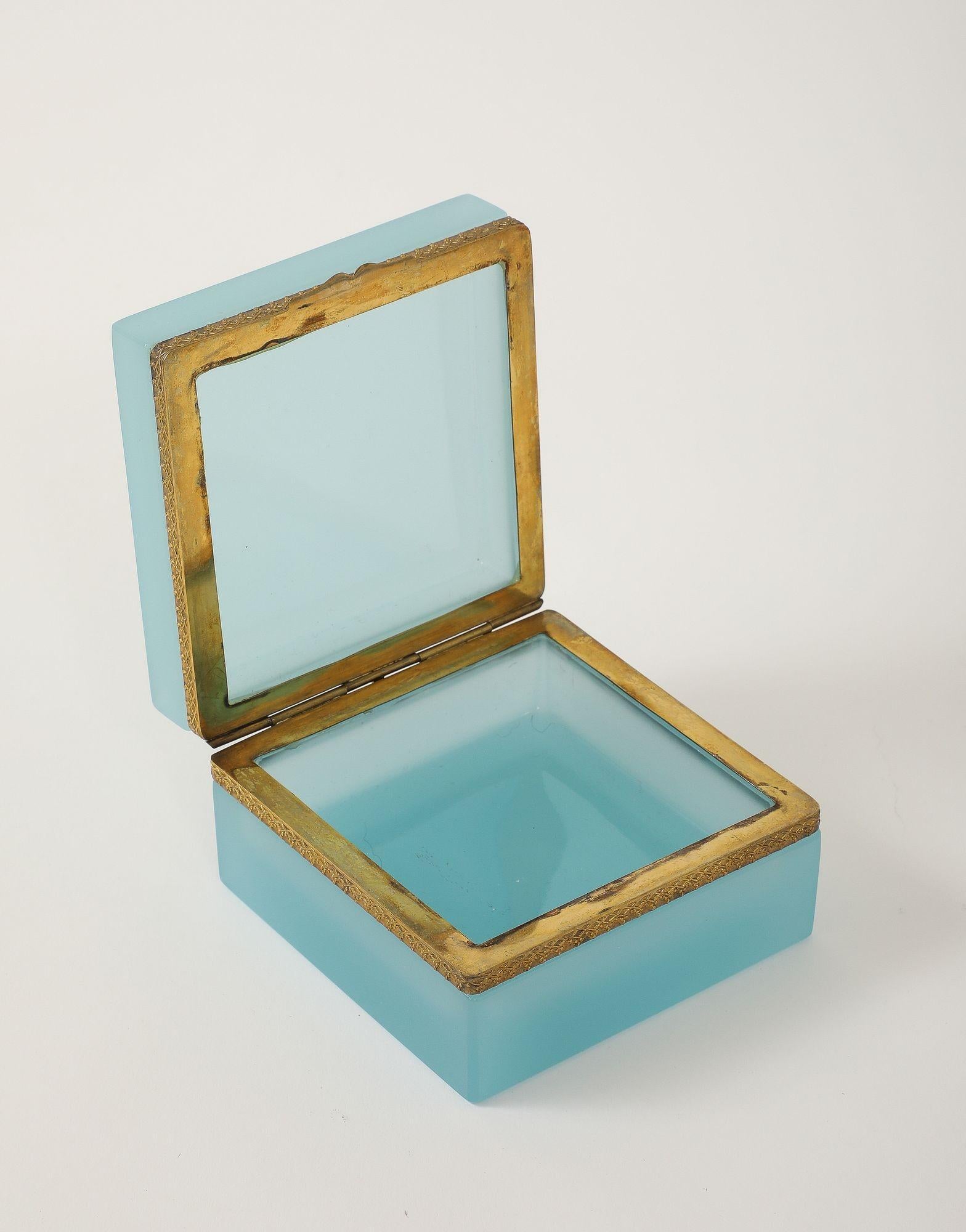 Boîte carrée en verre opalin d'une vibrante couleur bleu œuf de mer, datant du début du 20e siècle en France. Cette pièce remarquable présente des montures en laiton fantaisie d'origine et un couvercle à charnière, qui mettent en valeur le