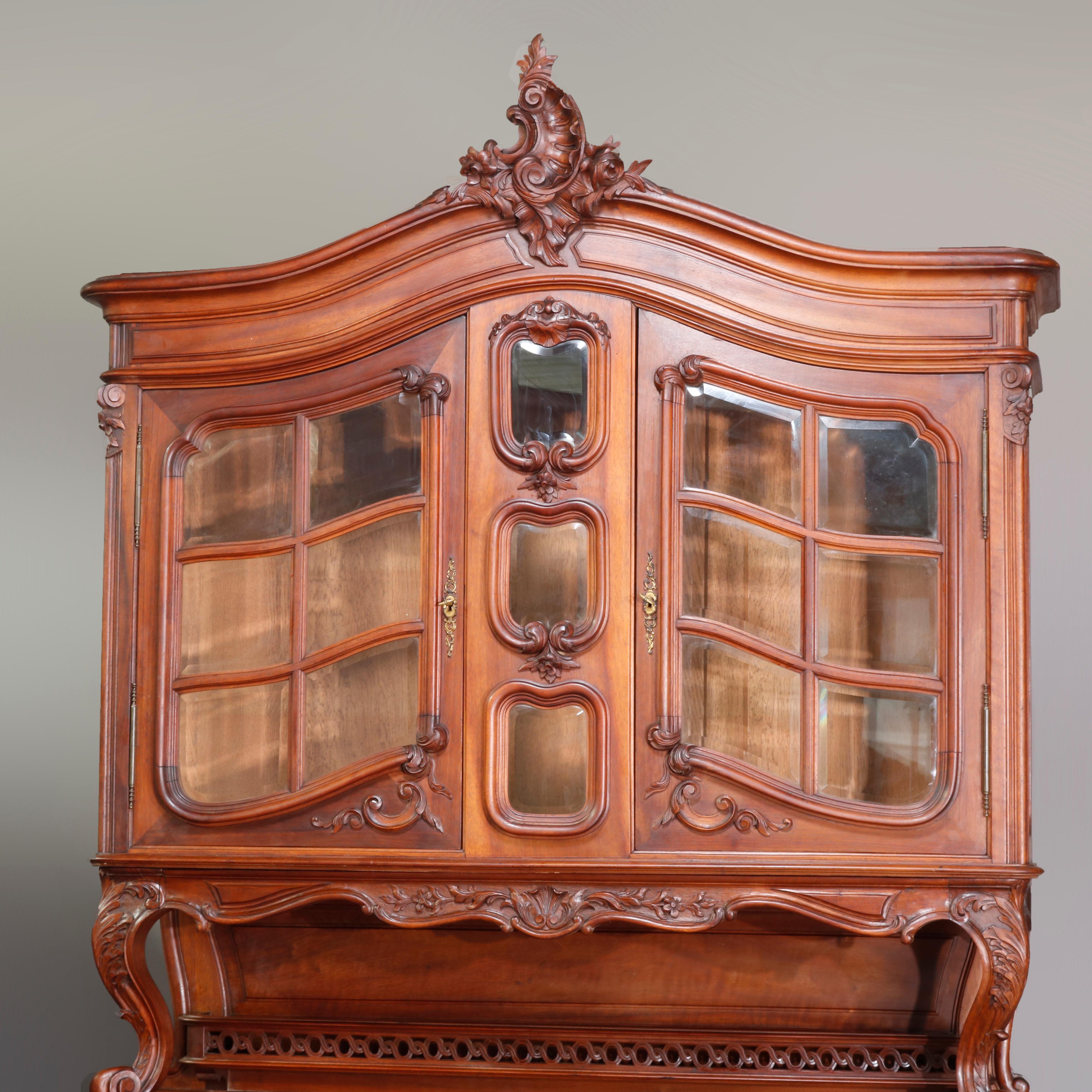 Antique French Rococo carved walnut cupboard with arched crest having foliate carved cartouche over shaped double doors with beveled panels and central beveled glass column, surmounting galleried backsplash with flanking acanthus scroll form