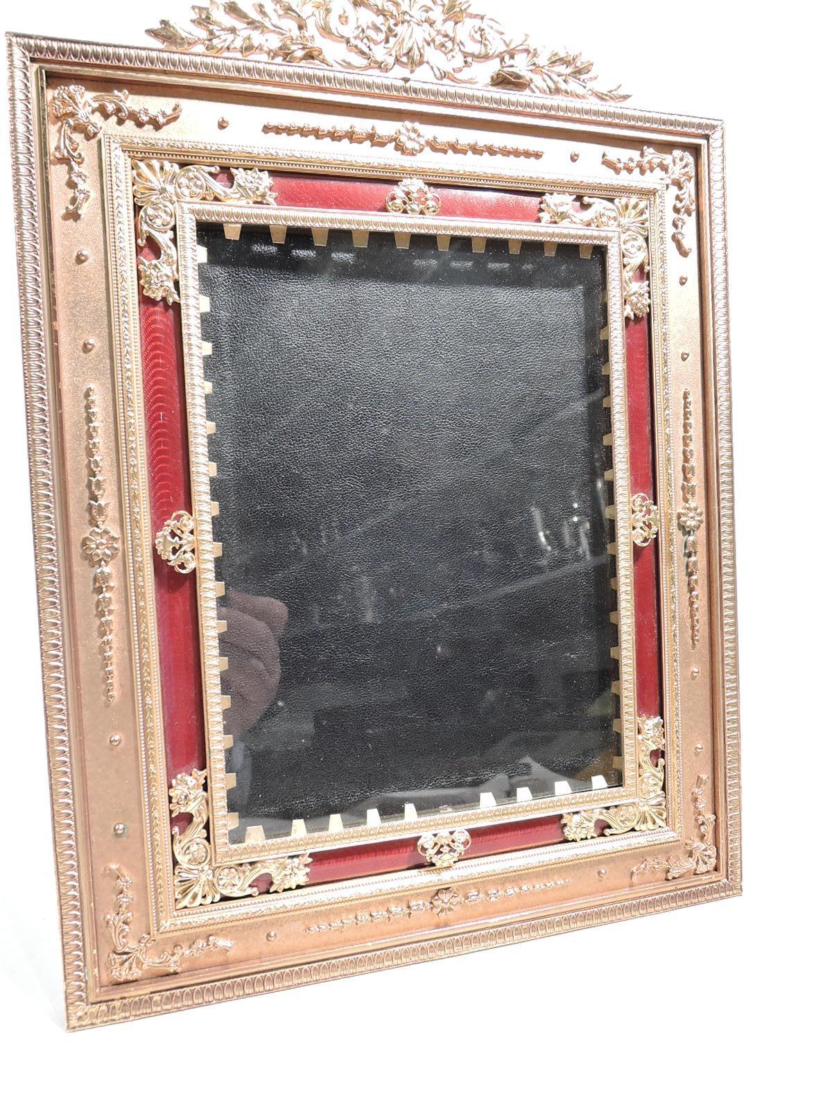Turn-of-the-century French gilt bronze picture frame. Rectangular window in same surround with raised leaf-and-dart, imbricated leaf, and beaded borders. Red guilloche border and applied and pierced flower baskets, cornucopias, bouquets and shells.