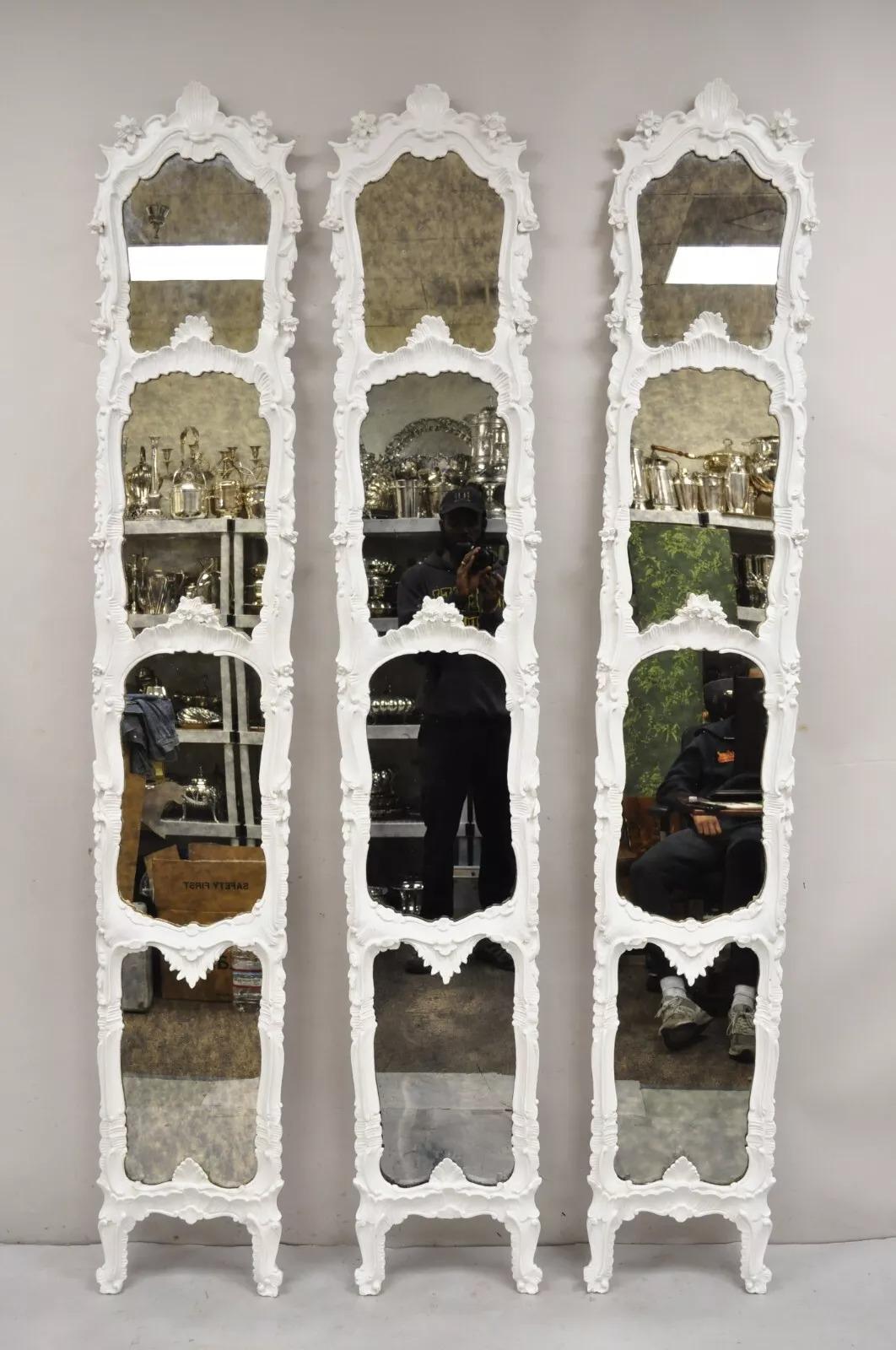 Antique French Rococo Louis XV Style White Carved Wood Tall Narrow Mirrors - 3 Pcs. Item features solid carved wood frames, white painted finish, floral carved accents, distressed/antiqued eglomise mirror, unique tall stately forms. Circa Early 20th