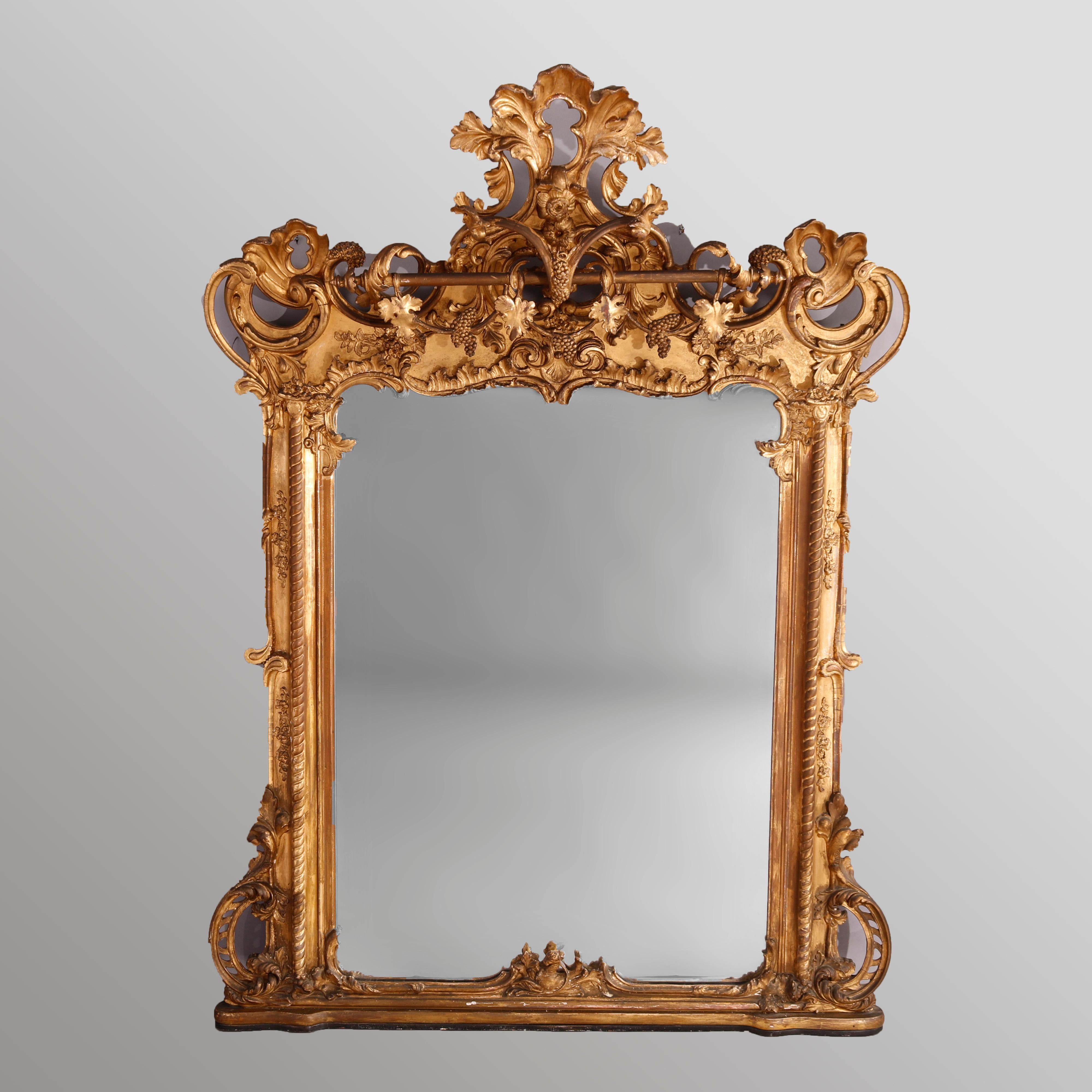 A large antique French Rococo over mantle pier mirror offers carved wood construction having gold leaf with pierced foliate crest over frame with scroll and foliate elements, 19th century

Measures- 79''H x 58''W x 16''D.
