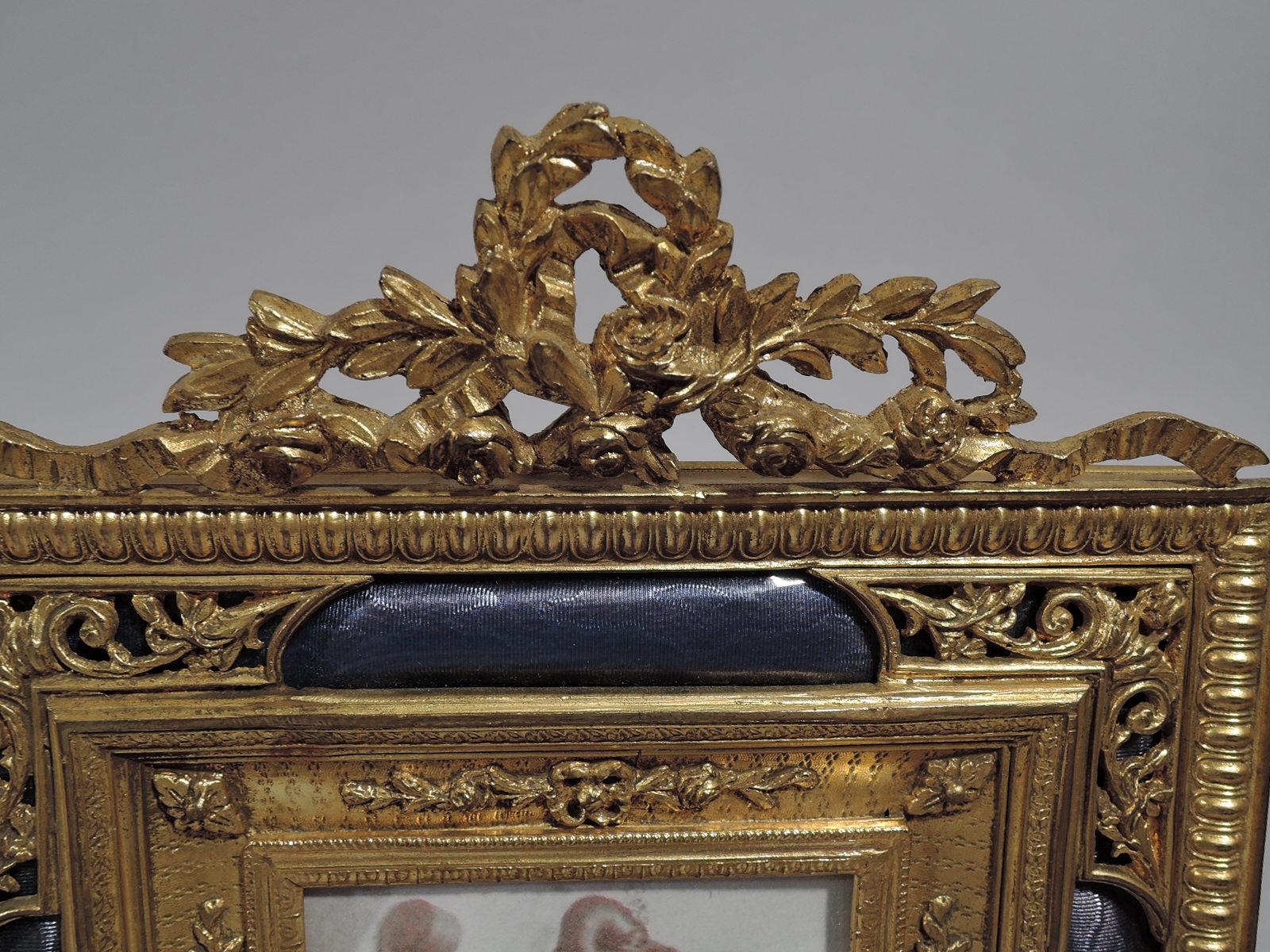 Turn-of-the-century French gilt bronze picture frame with lilac enamel. Rectangular window in concave surround with applied garlands in turn surround by wraparound tubular lilac enamel covered with pierced ornament at corners. Beaded, imbricated
