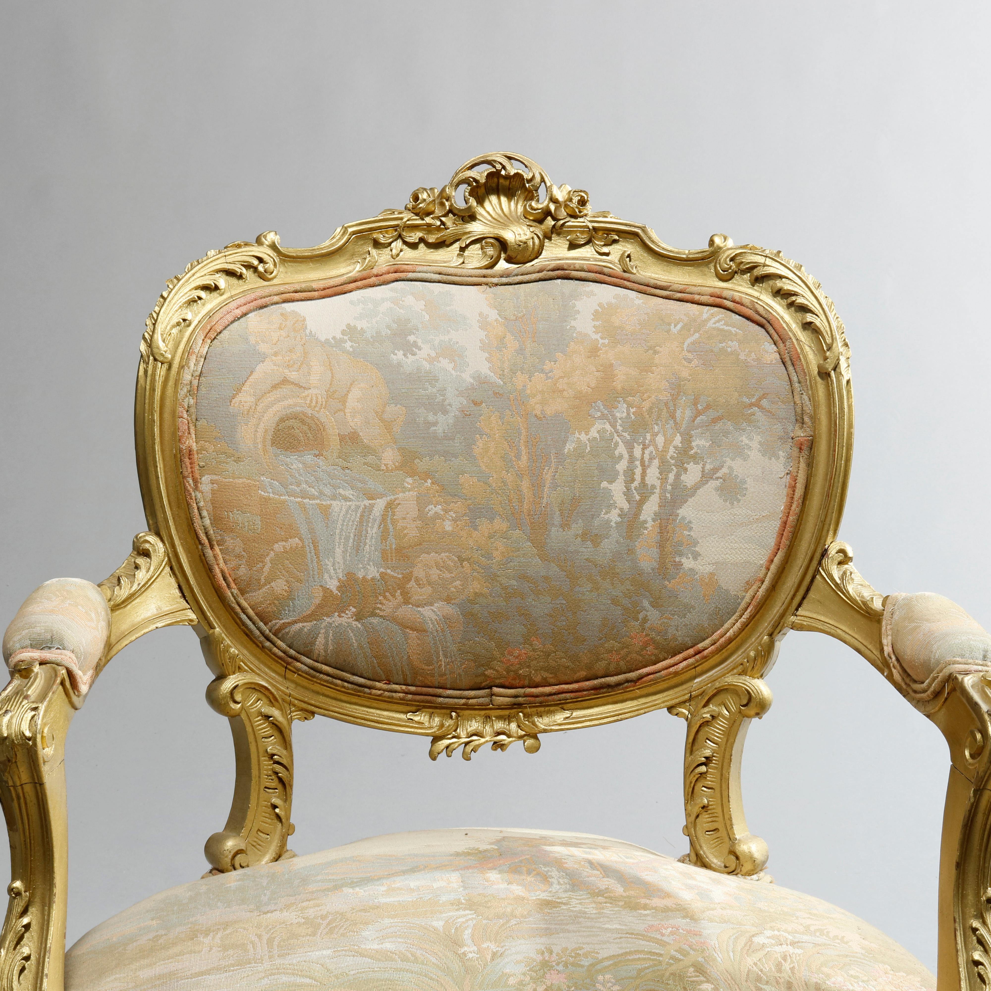 An antique French Rococo three-piece parlor set offer giltwood frames with pierced stylized shell crests over acanthus, foliate and scroll frame with tapestry seats, arms and backs having Classical scenes with cherubs, landscape and structures,