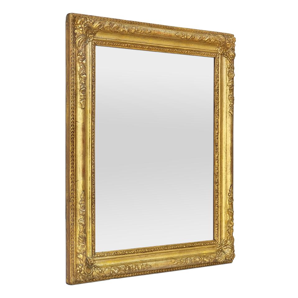 Antique French gilded wood mirror from the Romantic period, circa 1830. Decorated with garlands of flowers in the corners and a frieze of piastres. Antique frame re-gilding patinated with leaf. Frame width: 7 cm /  2.75 in. Modern glass mirror. Wood