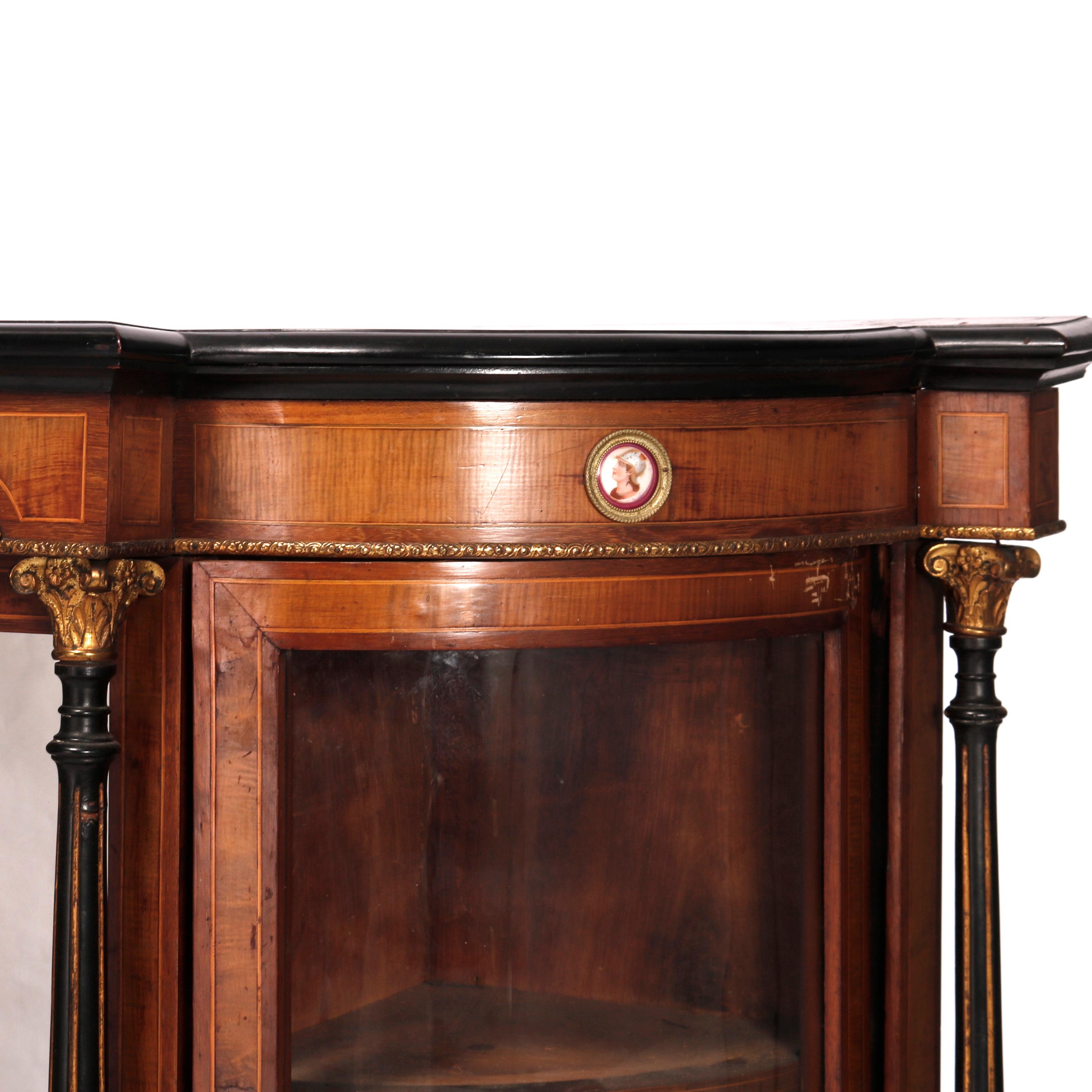 An antique French Classical credenza offers rosewood and burl construction in demilune form with beveled and paneled top over case with central double door cabinet with flanking mirrors and Corinthian column supports, and curved glass corner
