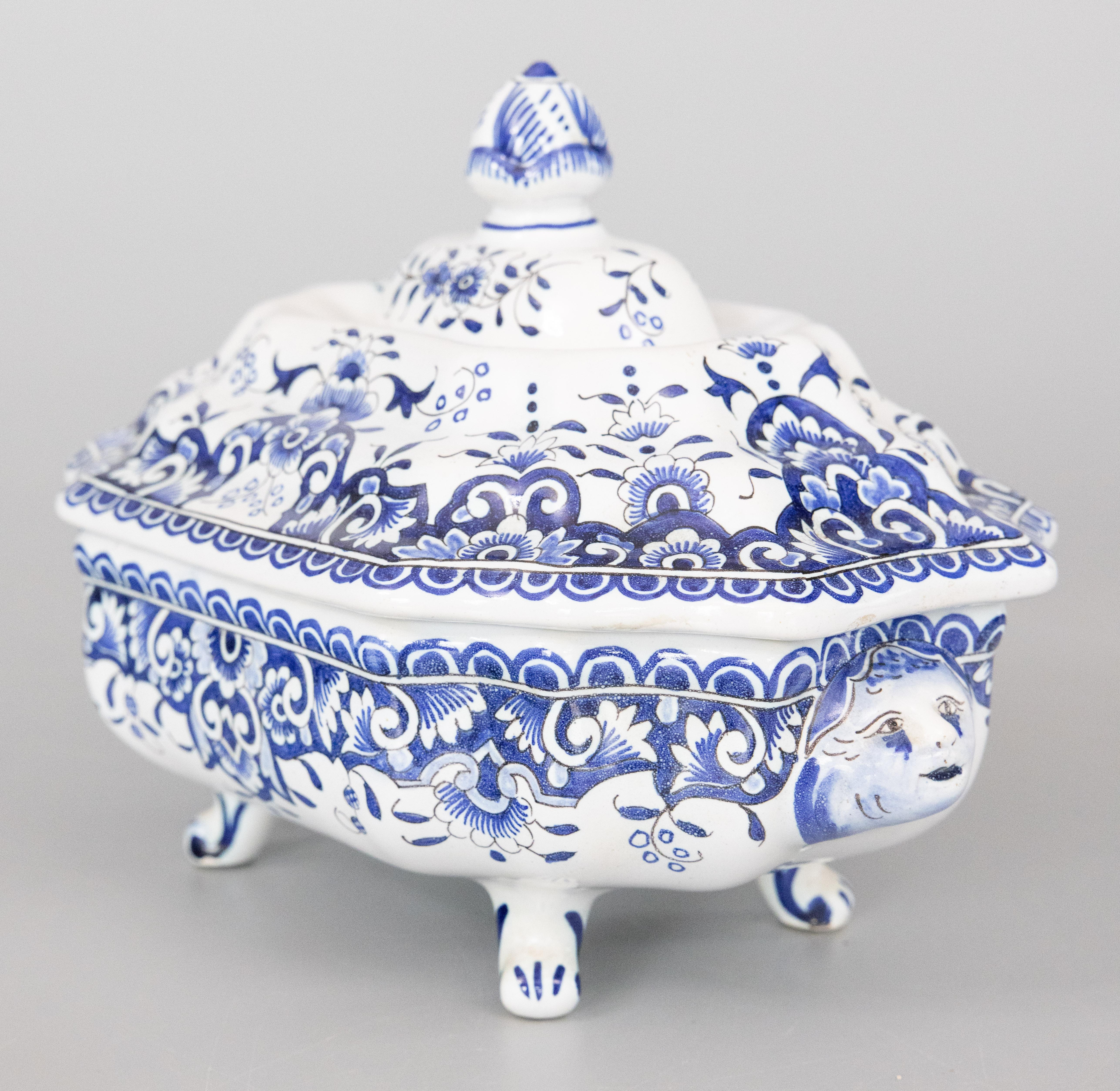 A lovely antique French Rouen faience blue and white ironstone soup tureen, circa 1900. No maker's mark. This gorgeous lidded tureen is decorated with floral designs, mythical creature handles, and charming feet, hand painted in in the traditional