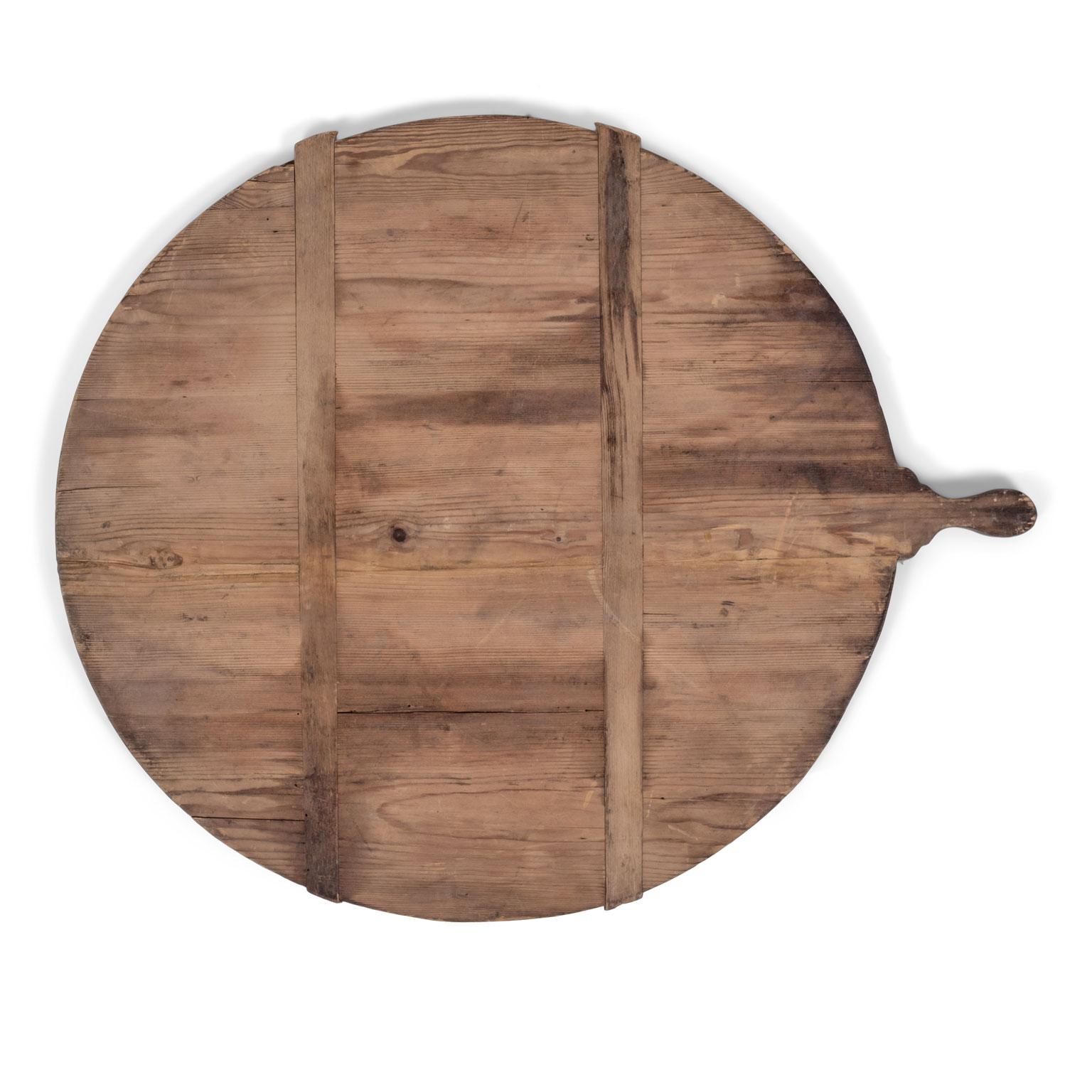 Antique French round bread board (or dough board), circa 1880-1910. Large round stripped pine bread board, under-girded with two cross slats to prevent warping. Nicely shaped handle.