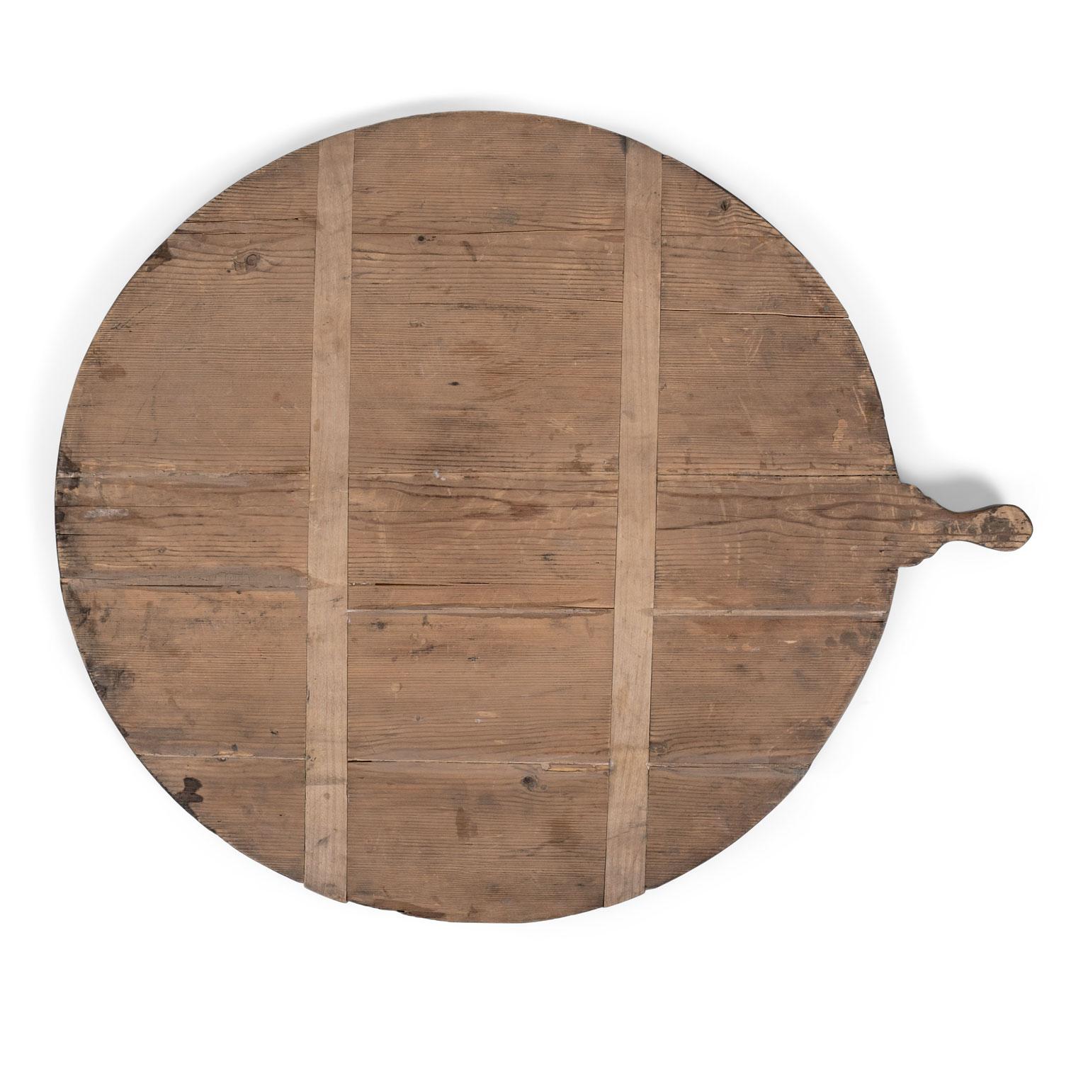 Antique French round bread board (or dough board), circa 1880-1910. Large round stripped pine bread board, under-girded with two cross slats to prevent warping. Nicely shaped handle.