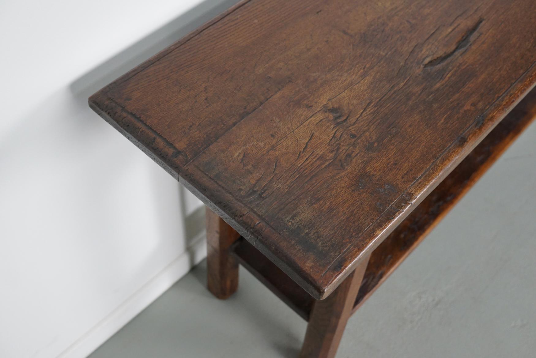 Cette élégante table a été fabriquée en France à partir d'une ancienne table en chêne aux magnifiques veinures. Elle a une couleur chaude avec une brillance profonde et la table montre de nombreuses marques d'utilisation et a une grande patine. 