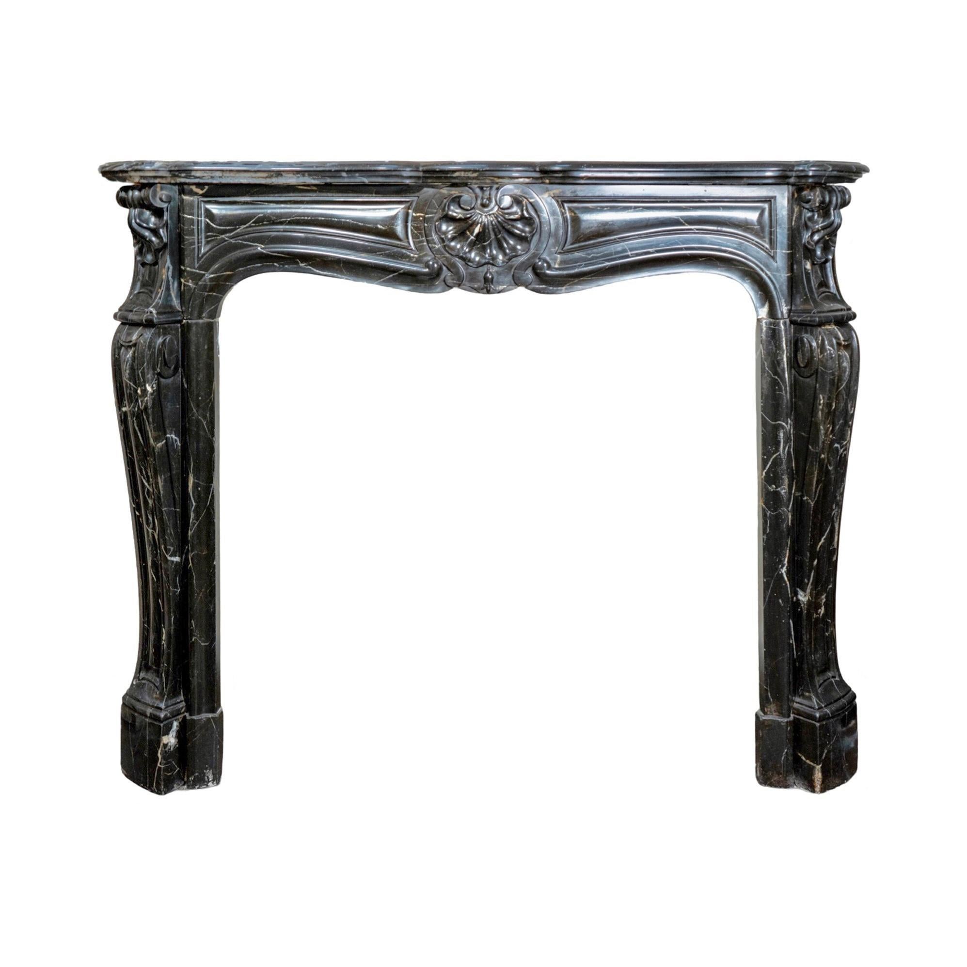 Une superbe cheminée de style Louis XV, fabriquée en France dans les années 1880 à partir de marbre noir de Sable, dégage une élégance intemporelle. Ses pieds pilastres moulurés, en forme de cabriole gracieuse, sont ornés de coquilles et de moulures