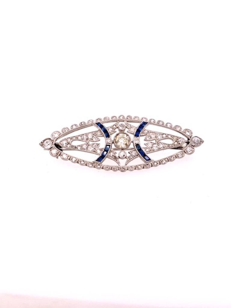 Antique pin, with lovely graceful cut-out pattern.  A mixture of old European cut, mine cut and rose cut diamonds, intersected by two curving rows of baguette sapphires.  Set in platinum.  1 7/8